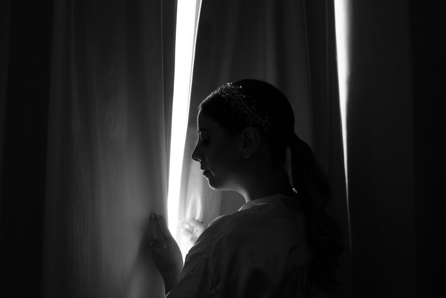Silhouette portrait of a person gazing through window light in black and white.