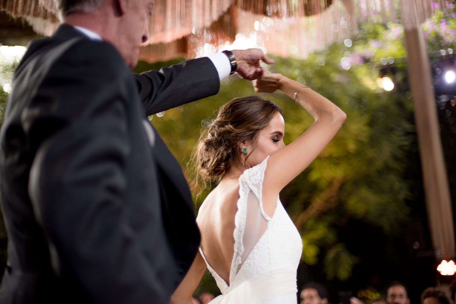 A couple performs an elegant twirl during their wedding dance under outdoor decorations.