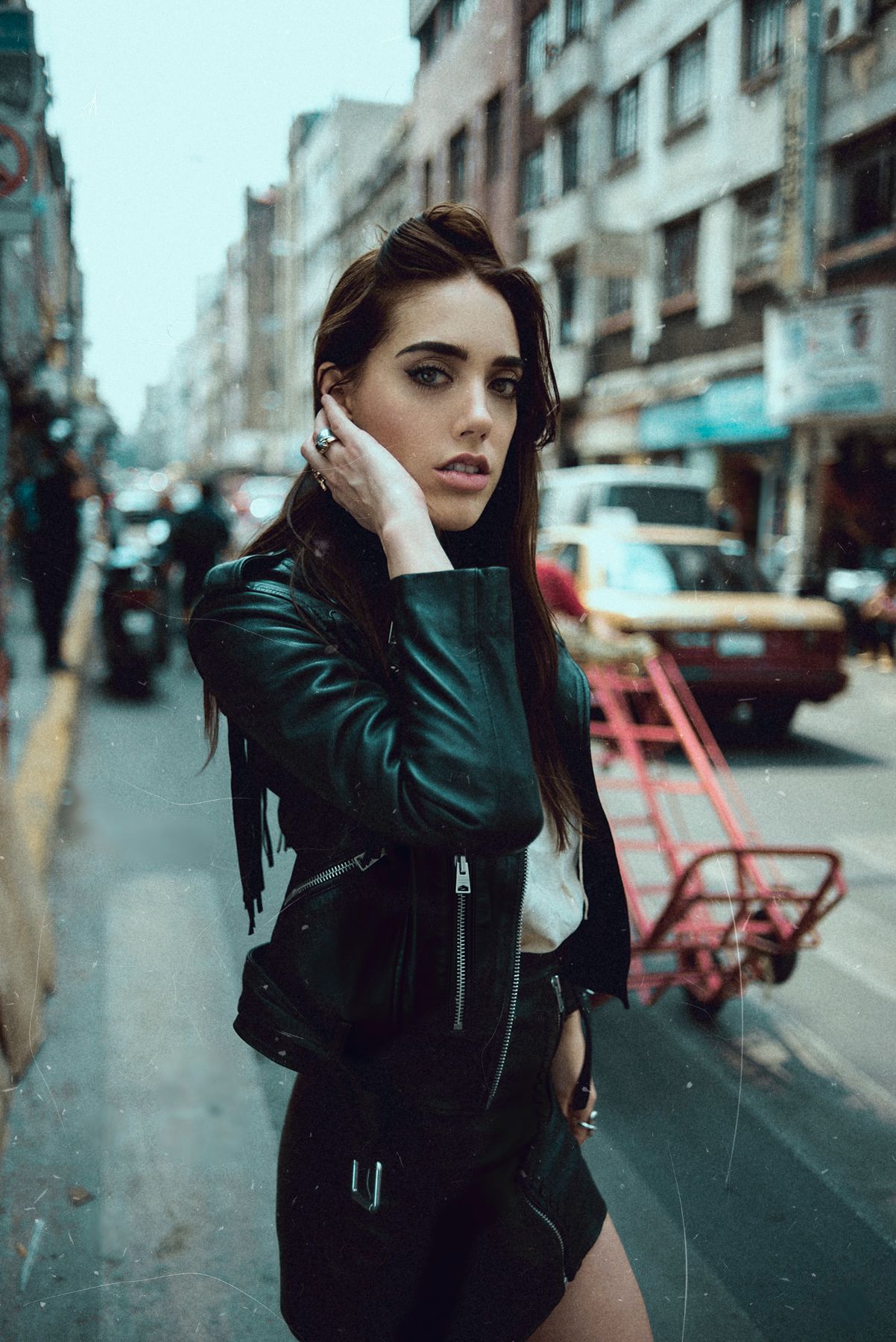 Moody street photography with leather jacket against urban city backdrop in rain.