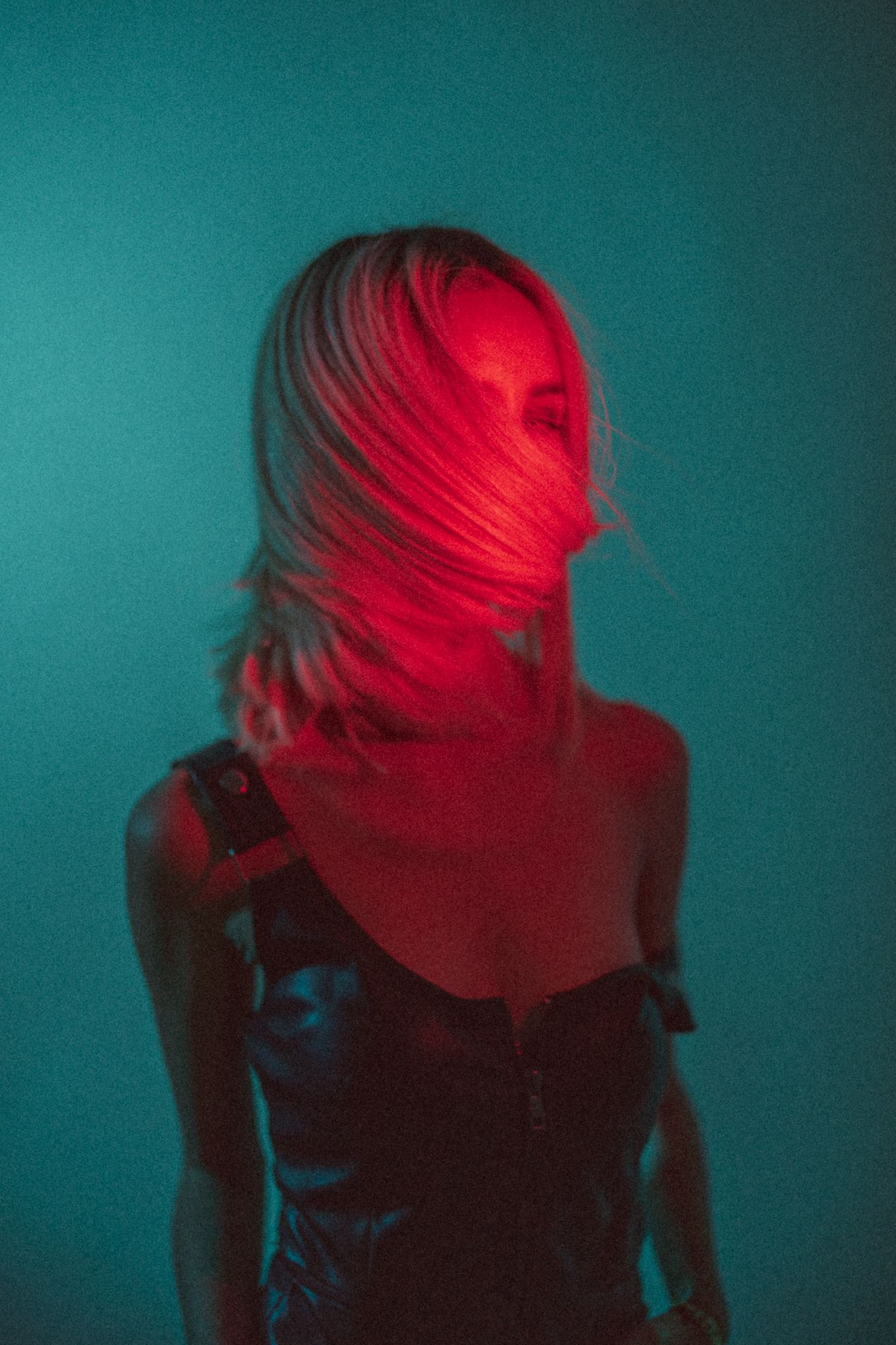 Abstract portrait with hair covering face in red and teal lighting.
