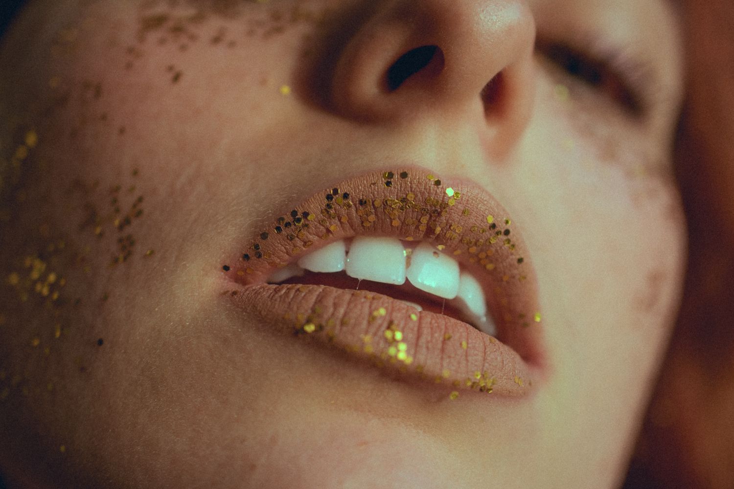 Macro shot of lips covered in gold glitter with glowing effect.