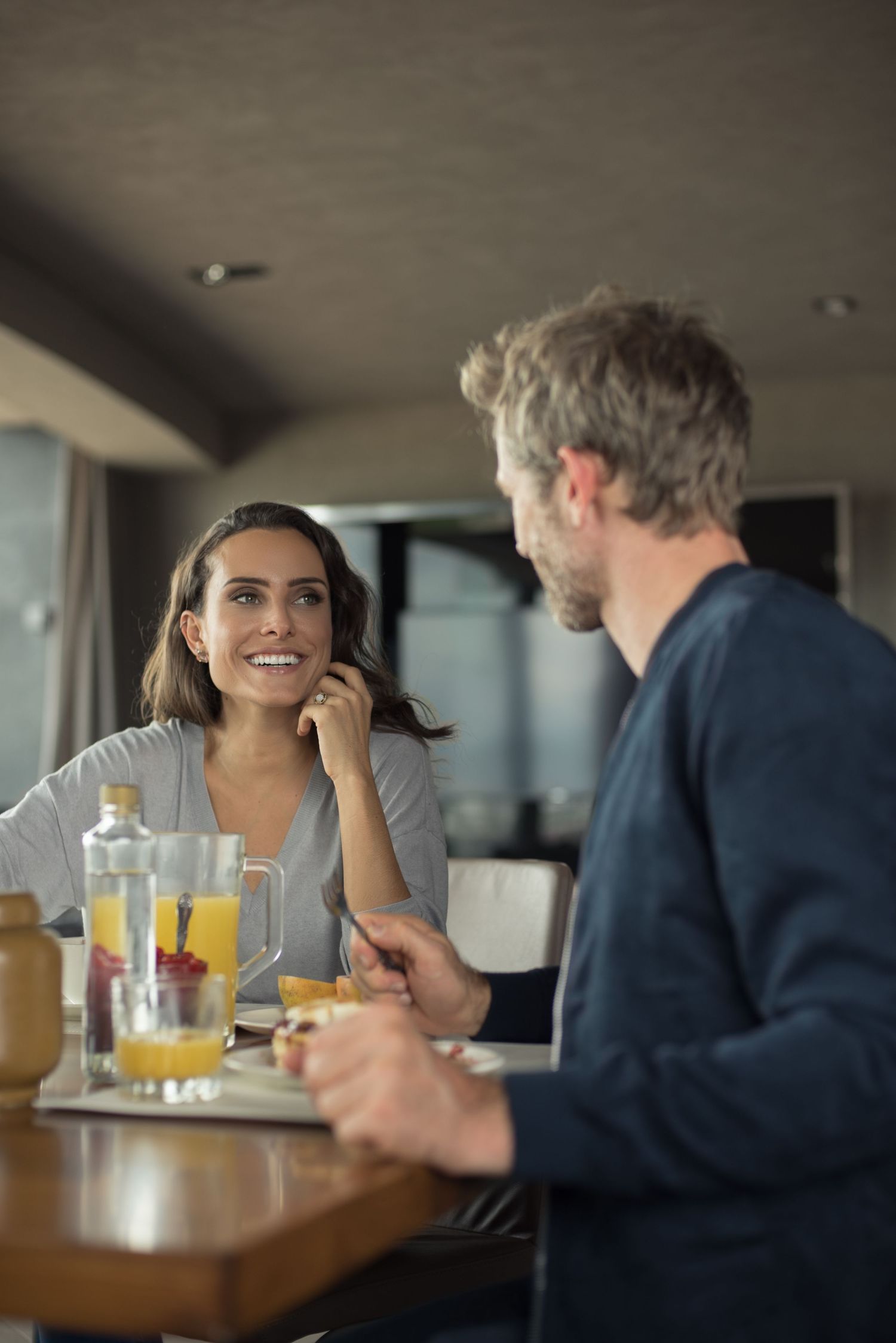 Two people engaged in animated conversation over drinks at a dining table.