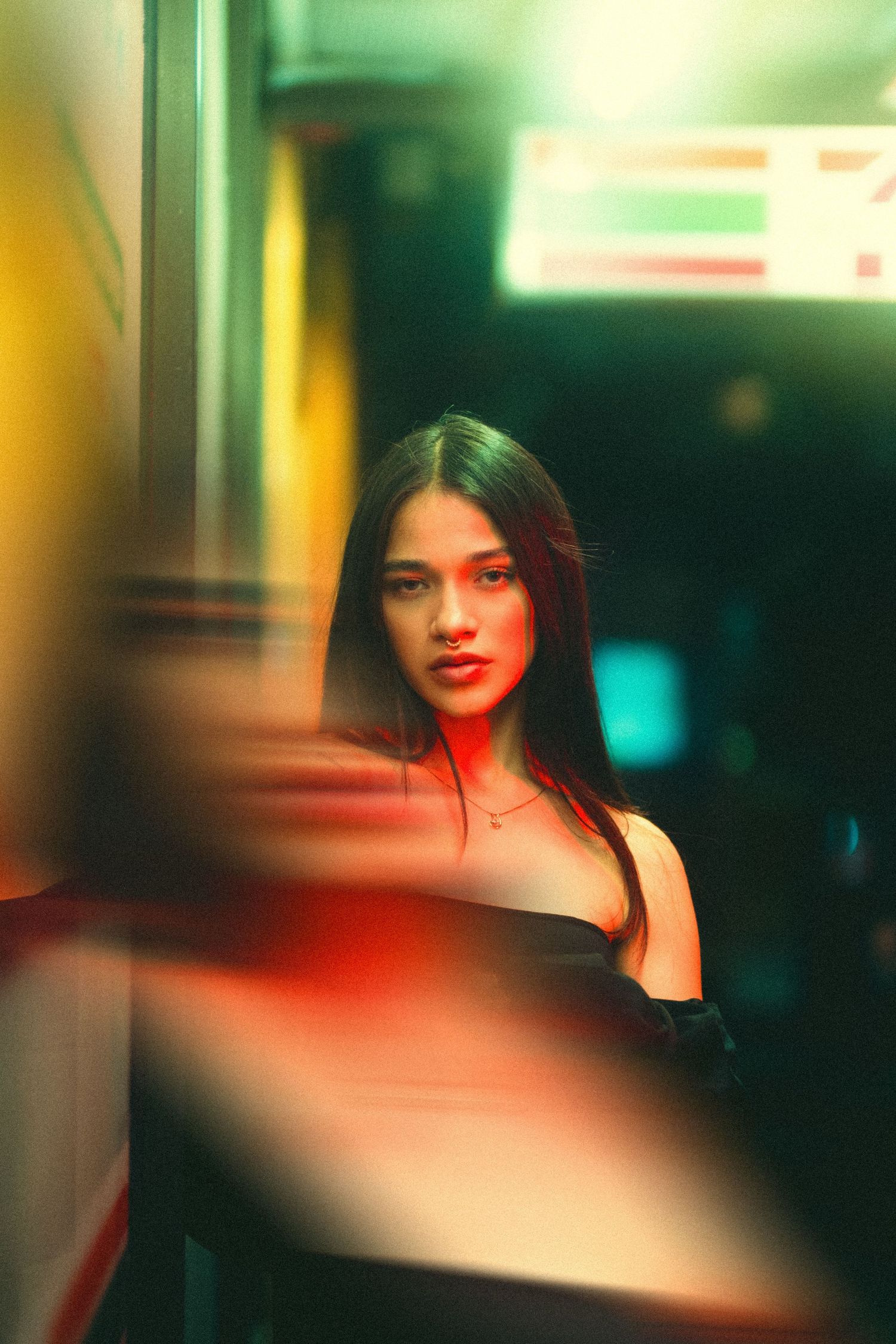 Artistic portrait photograph with vibrant red and green lighting effects creating a moody atmospheric ambiance.