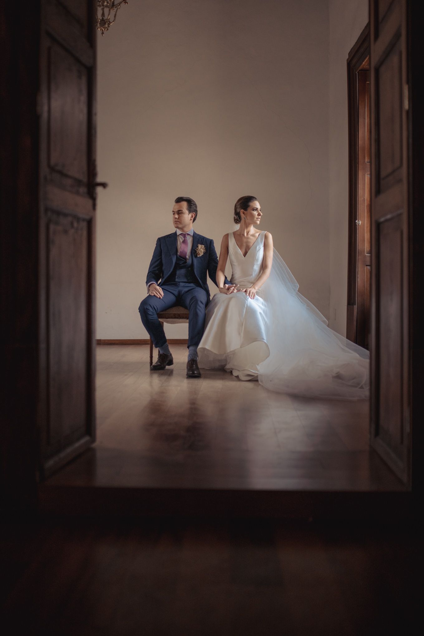 Newlyweds sit together in doorway for intimate wedding portrait.