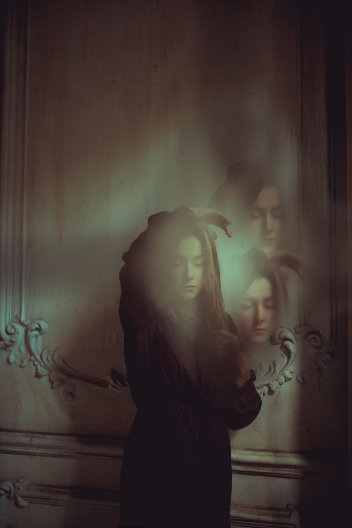 Multiple exposure portrait creating ghostly effect against decorative wall.