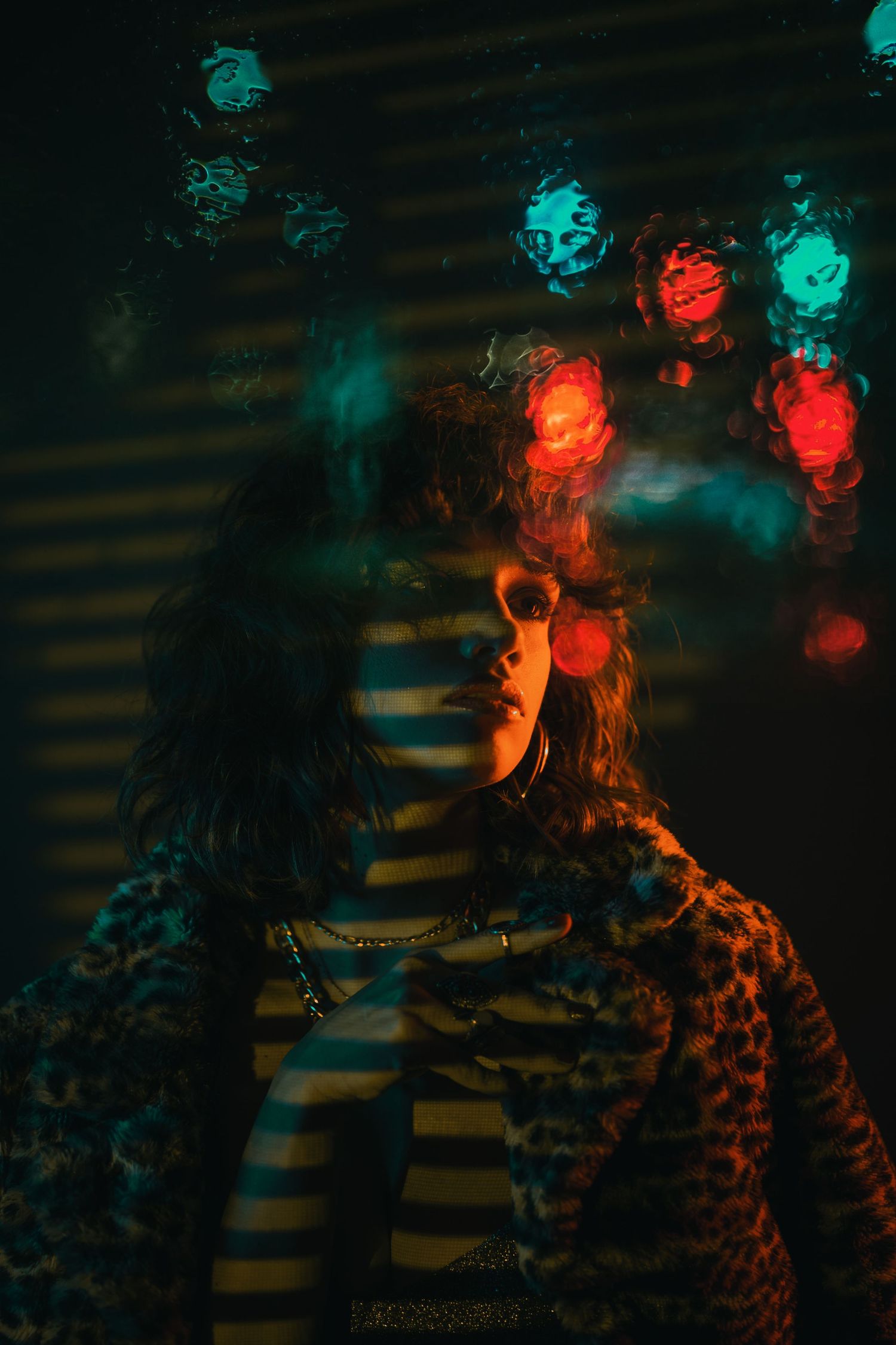 Artistic portrait with bokeh lights creating a moody atmosphere with red and turquoise glowing orbs in the background.