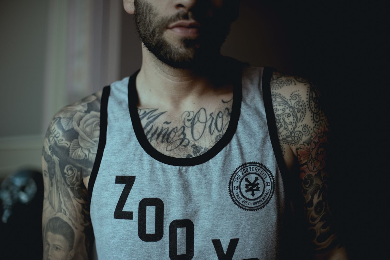 Close-up of grey athletic tank with 'Zoo Yo' branding and visible tattoo artwork.