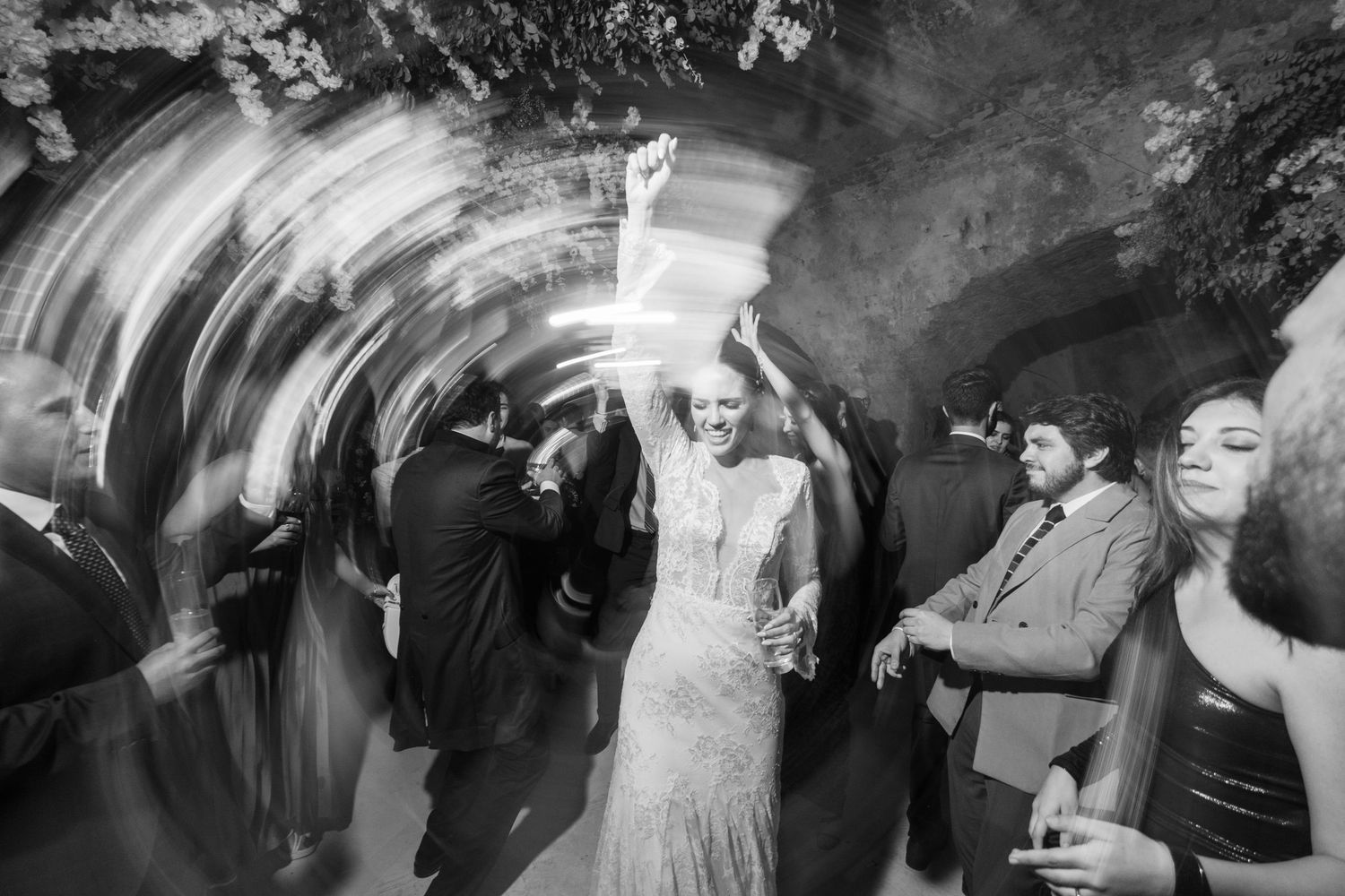 Black and white photo of wedding guests dancing with motion blur effects.