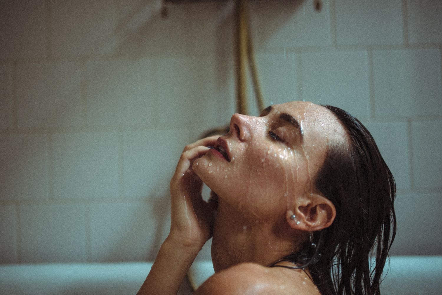 Artistic bathtub portrait with dramatic lighting and wet hair effect.