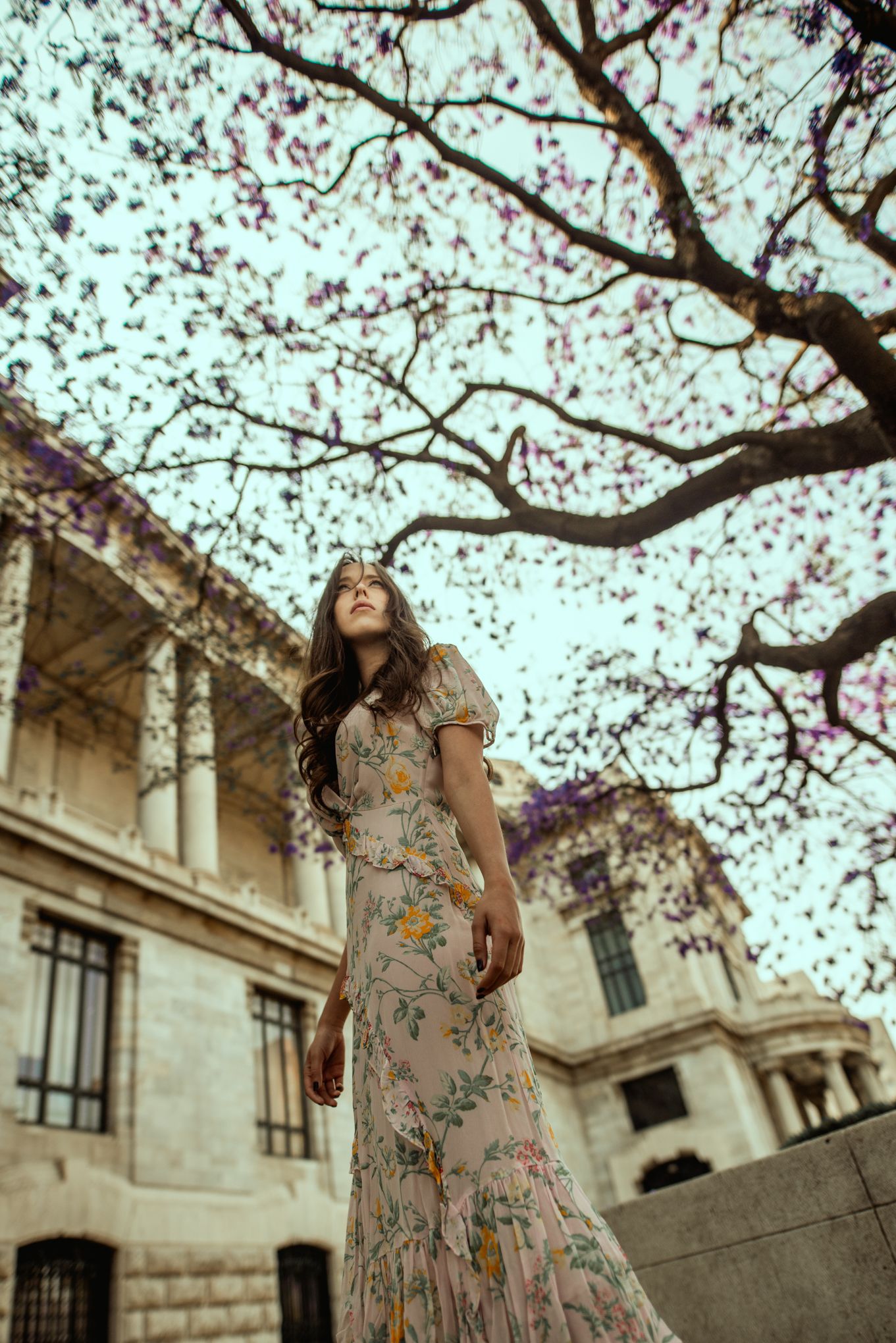 Romantic portrait under blooming spring trees near classic architecture.