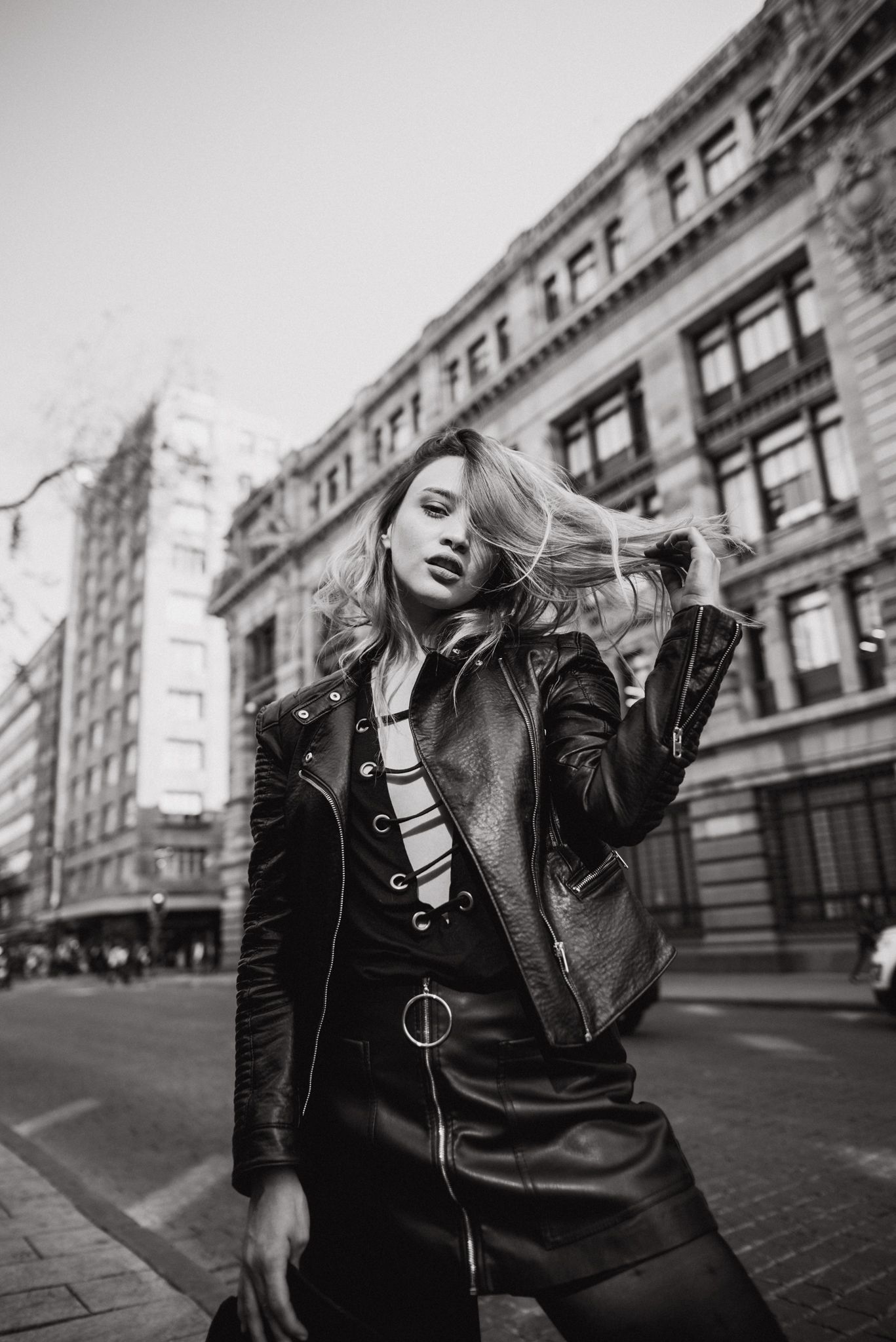 Urban fashion photograph of model in leather jacket against classic city architecture.