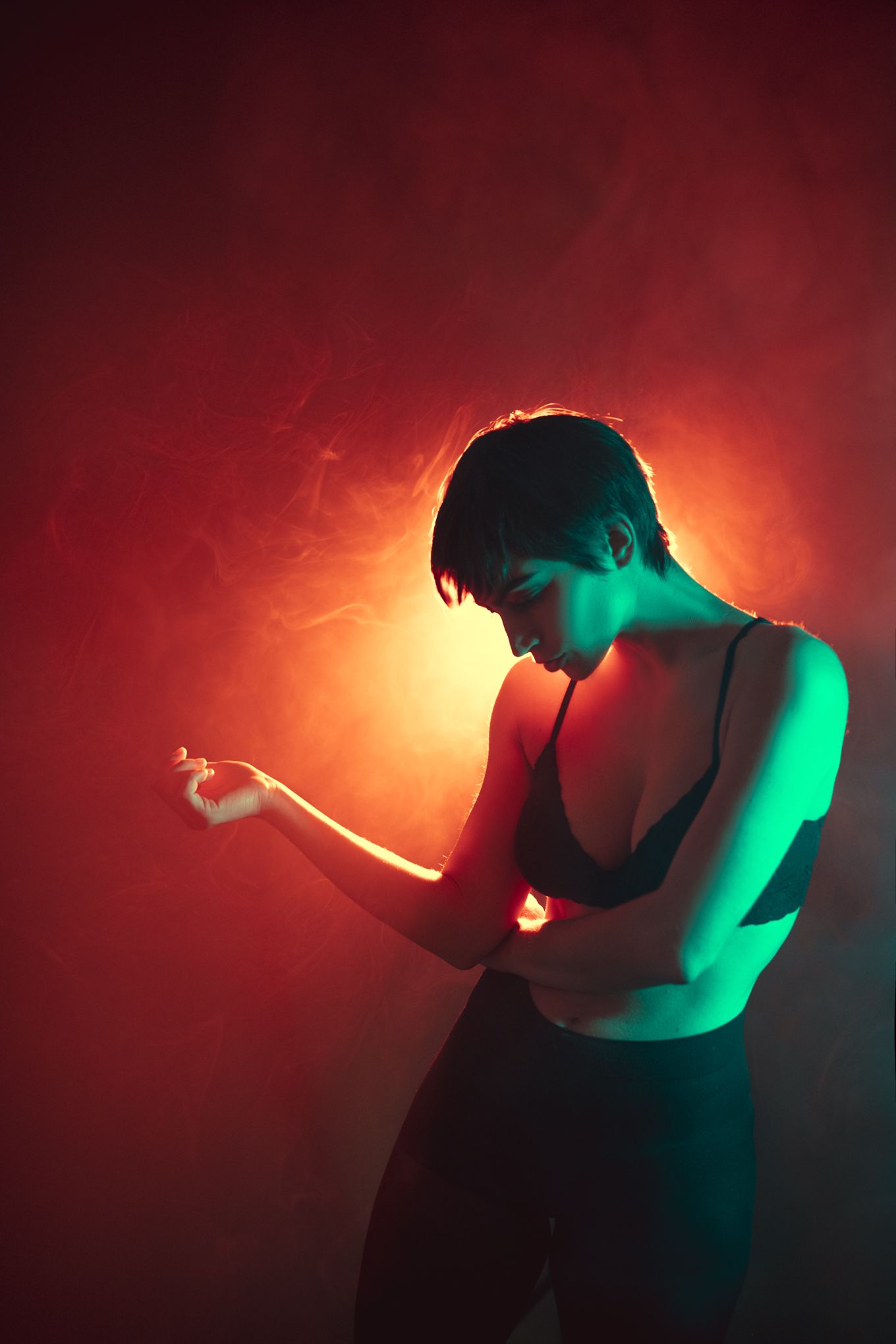 Silhouetted figure illuminated by dramatic red and green lighting holding a pose in dark atmosphere.