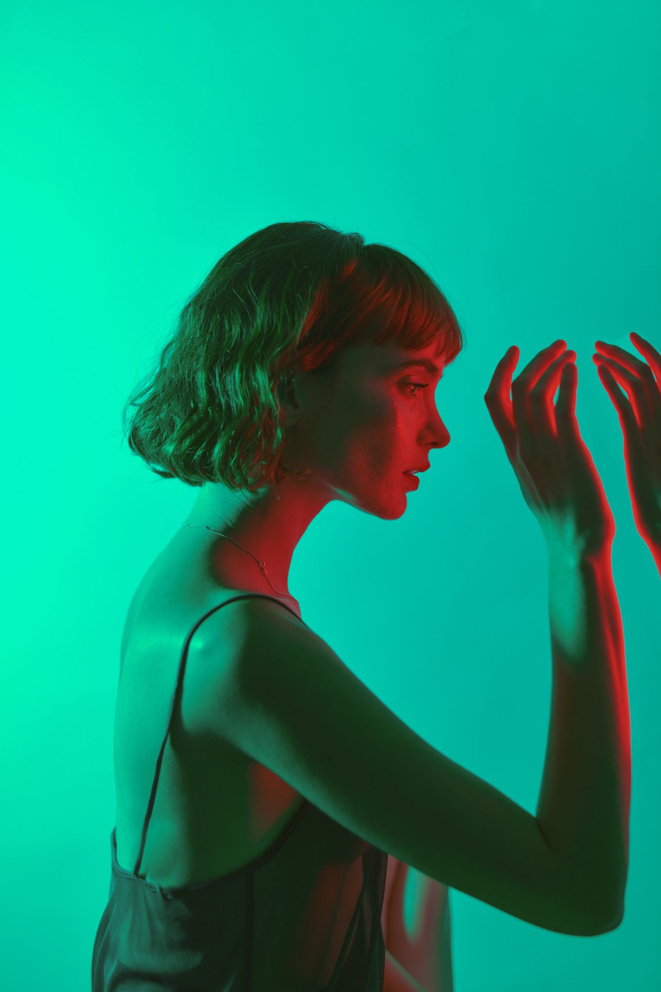 Side profile silhouette against turquoise background with red lighting effects.