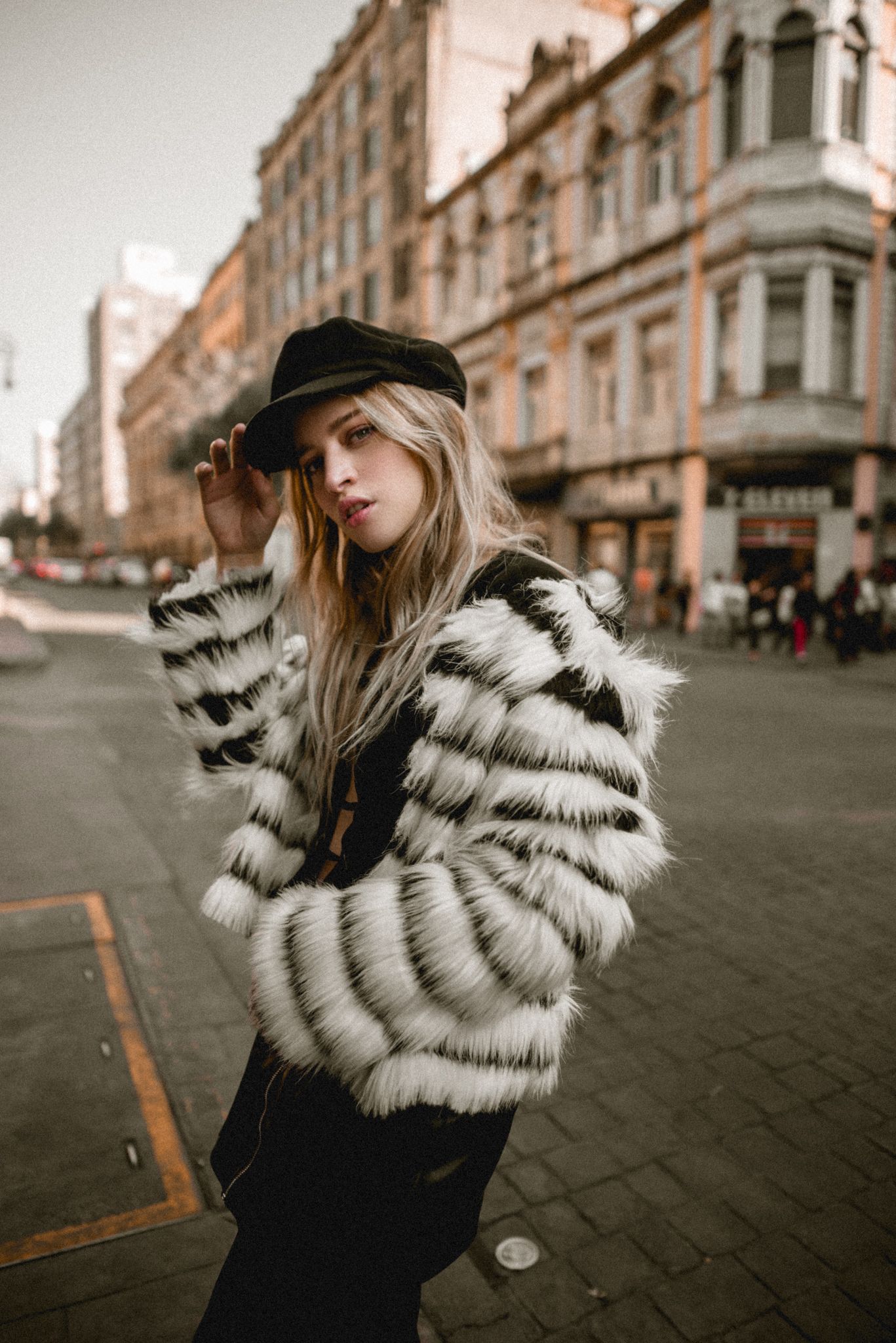 Fashion portrait of model in black and white striped faux fur coat on city street.