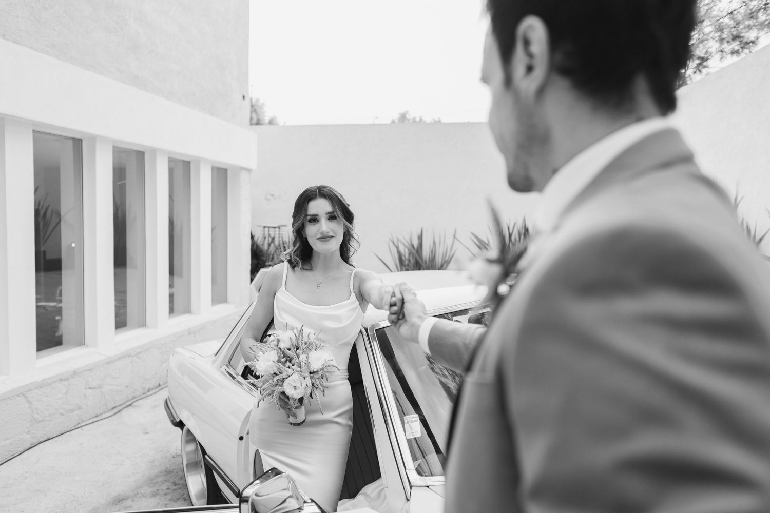 Black and white photo of a classic car arrival at a wedding.