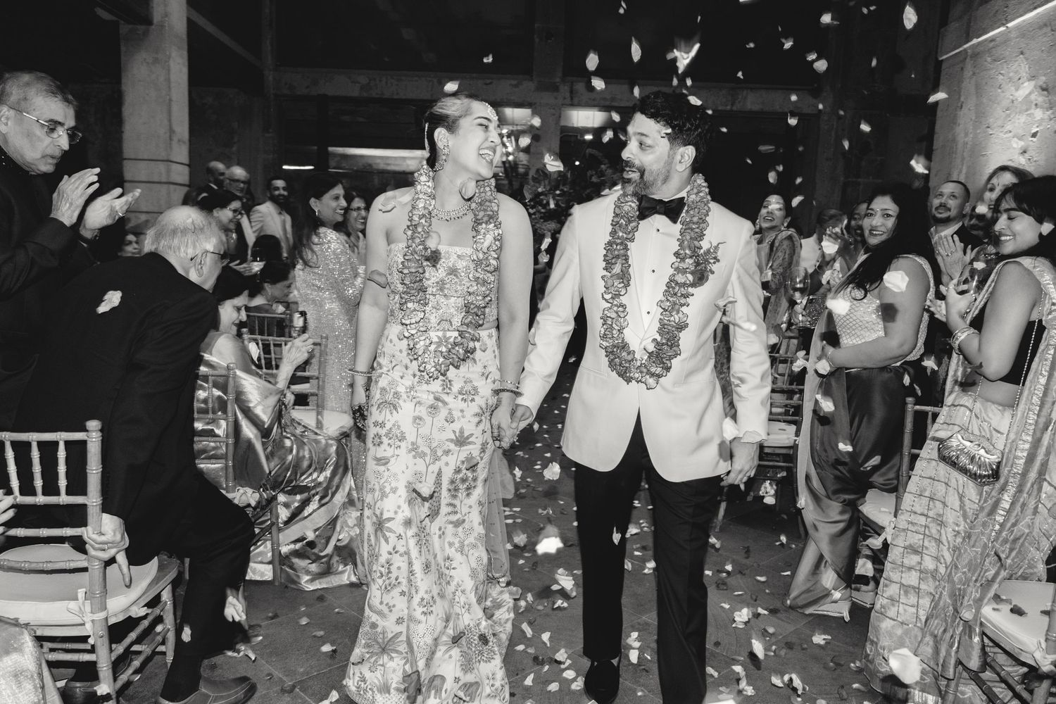 Wedding couple walks down aisle as guests throw confetti during joyful reception exit celebration.