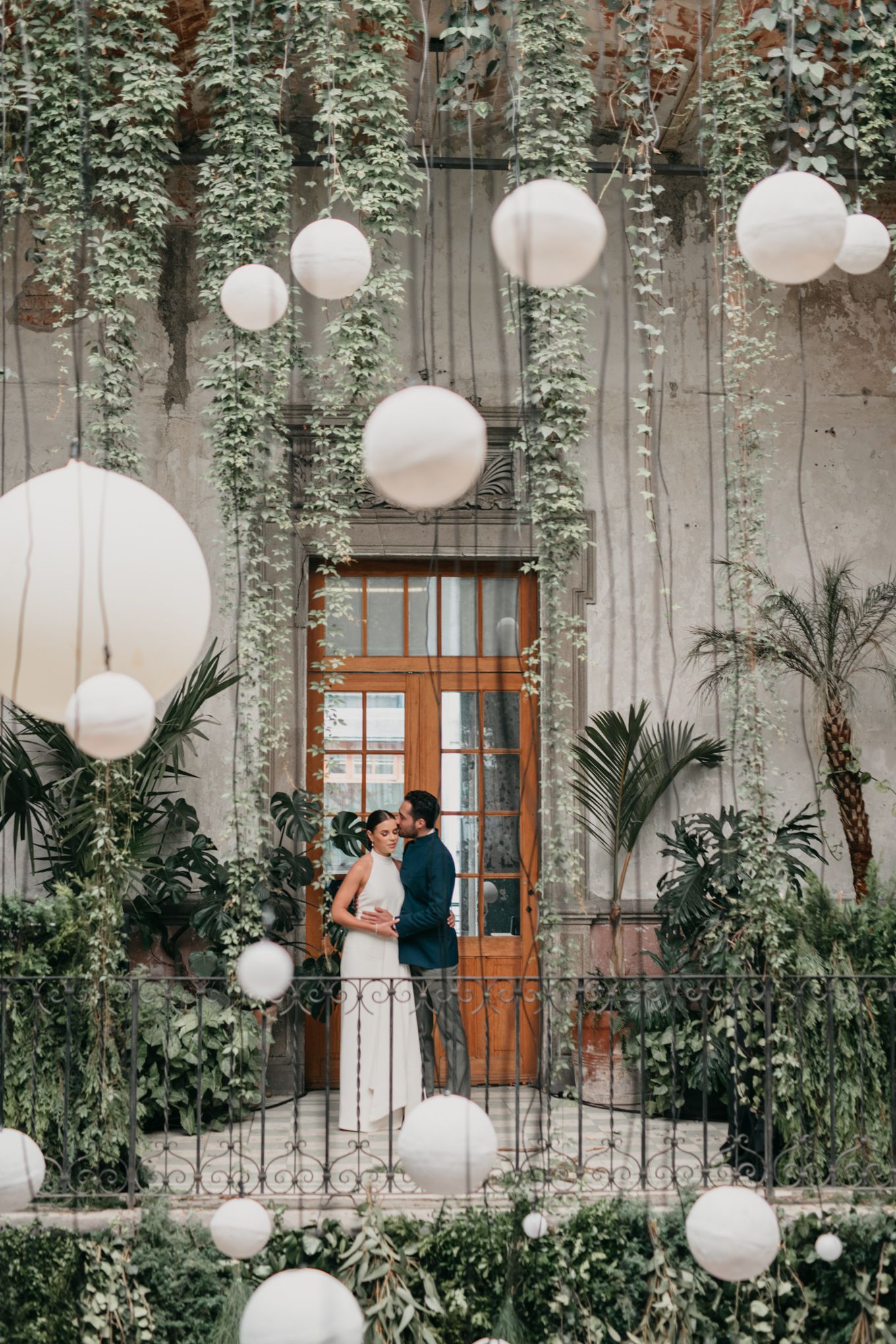 White paper lanterns and cascading greenery adorn a romantic industrial door entrance decorated for a wedding celebration.