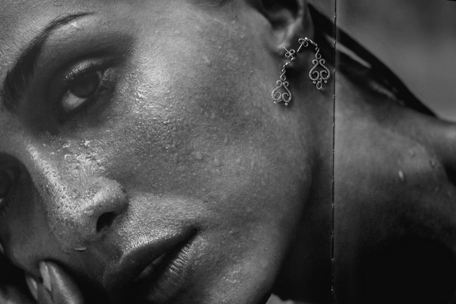 Black and white artistic portrait capturing dramatic lighting on skin texture and an elegant dangling earring.