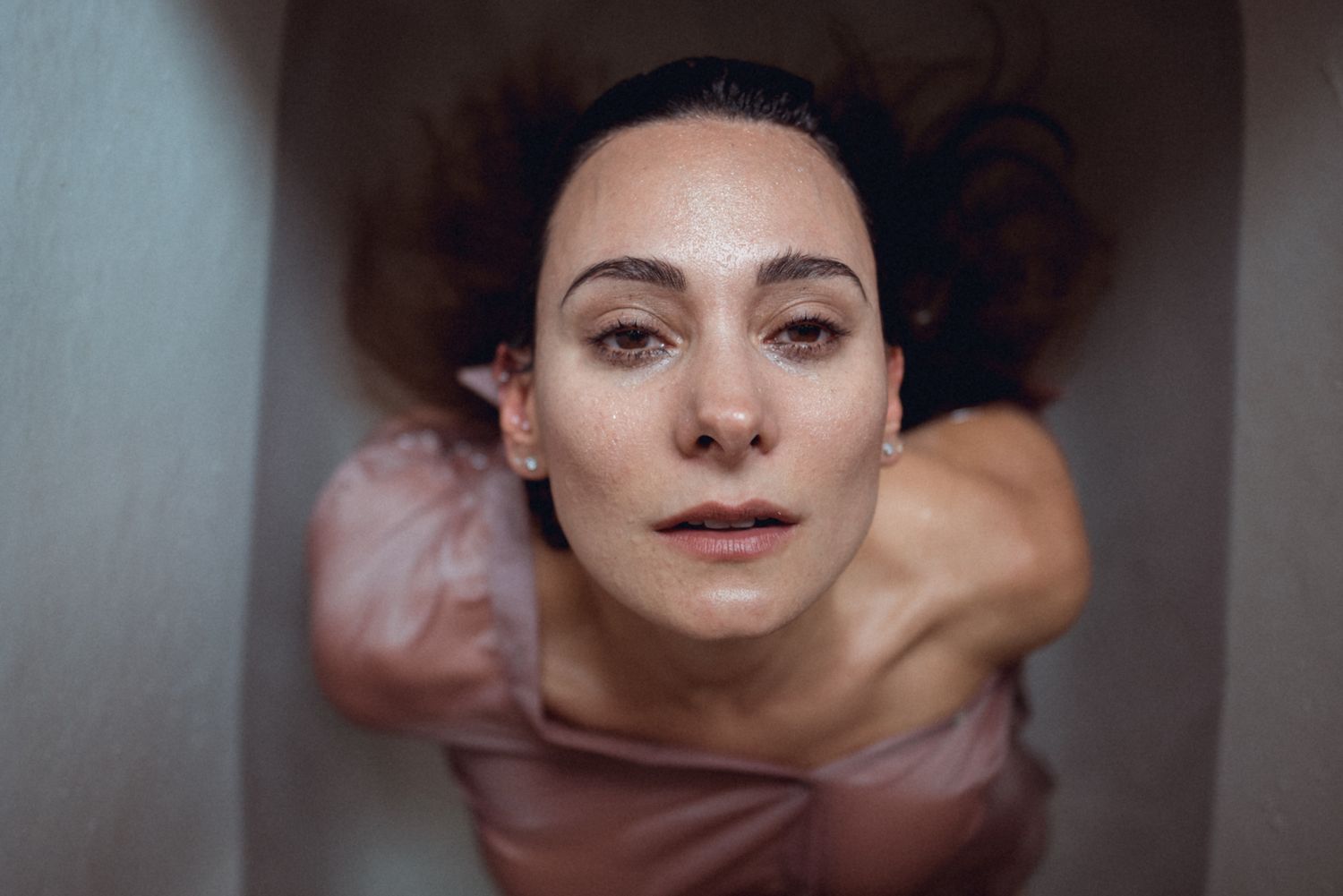 Intimate close-up portrait with natural makeup and pink fabric.