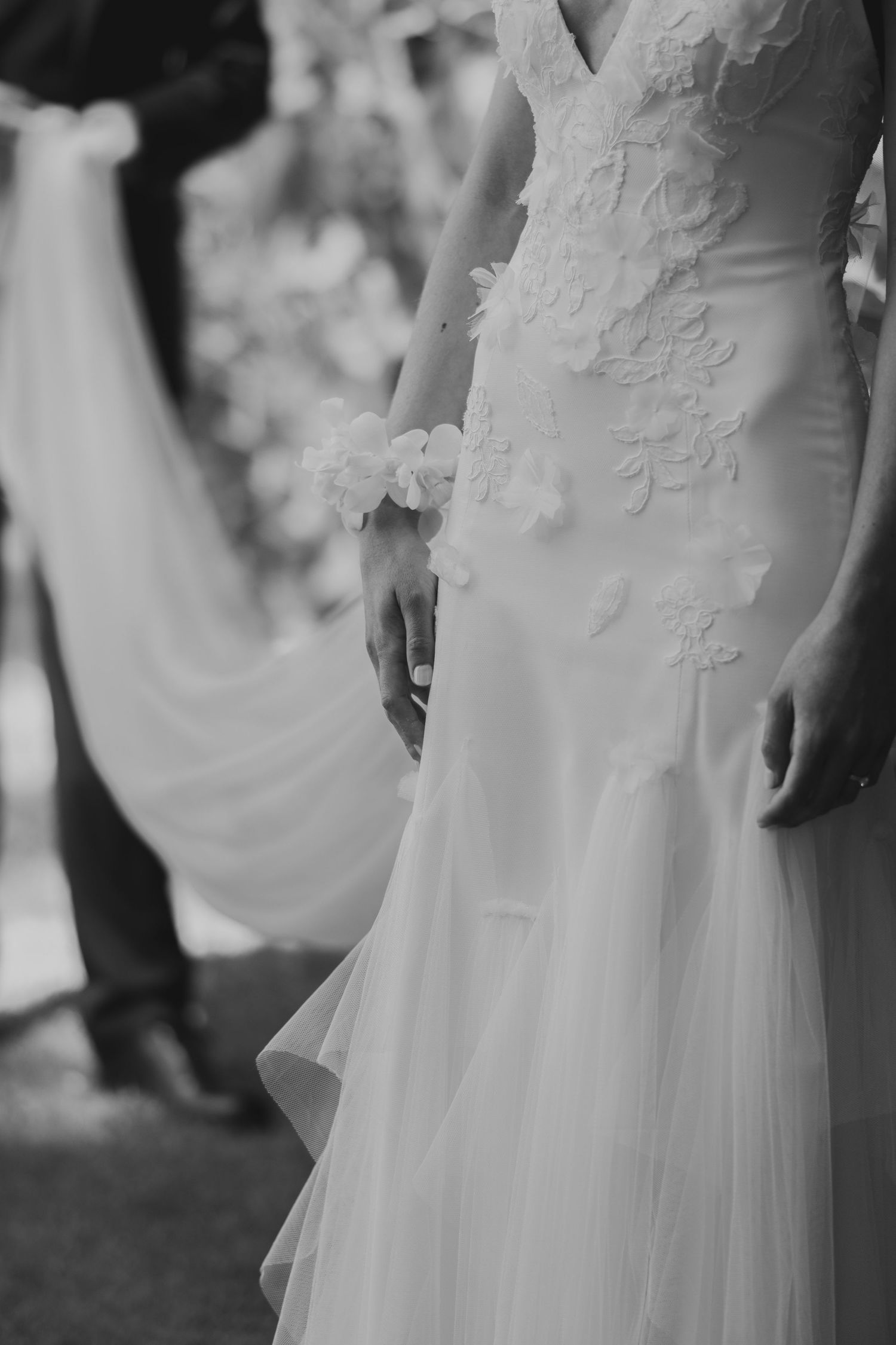 Detail shot of delicate lace appliques on a flowing white wedding dress.