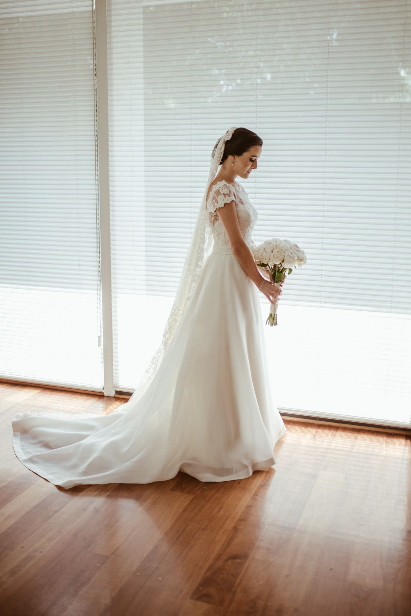 Full-length view of bride in classic white gown with lace details and flowing train.