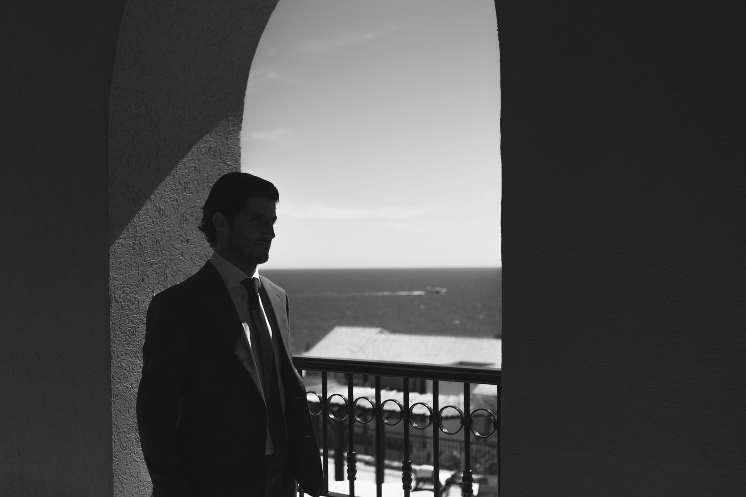 Dramatic silhouette of figure standing in archway overlooking ocean view.