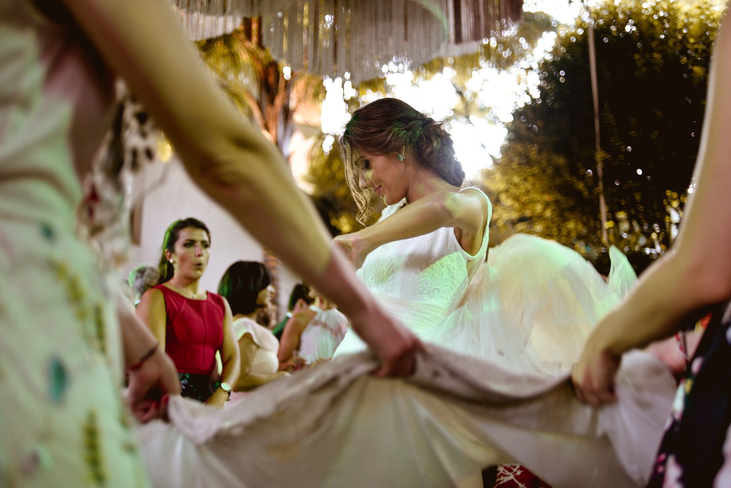 Wedding guests dancing and swirling a white dress at an outdoor evening reception.