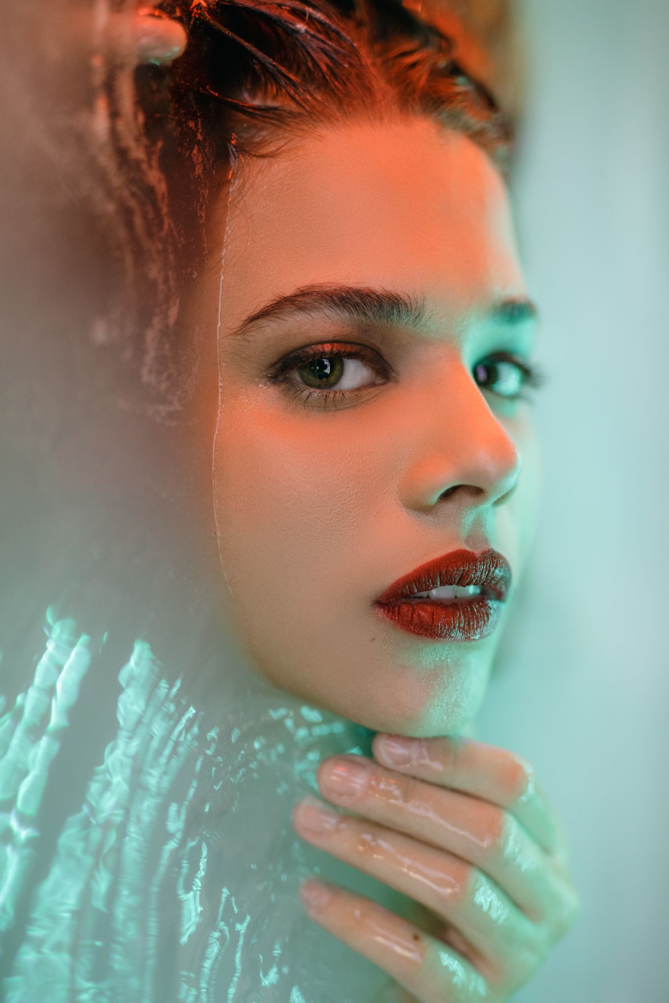 Beauty portrait with dual-toned lighting creating a split effect between warm orange and cool turquoise.