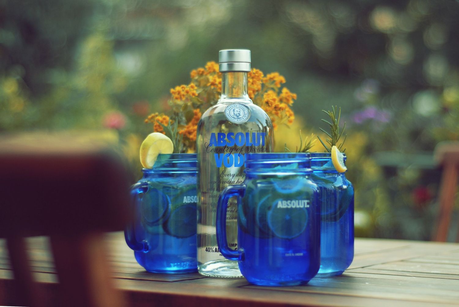 Blue glass bottles and perfume containers arranged artistically in sunlight on wooden surfaces.