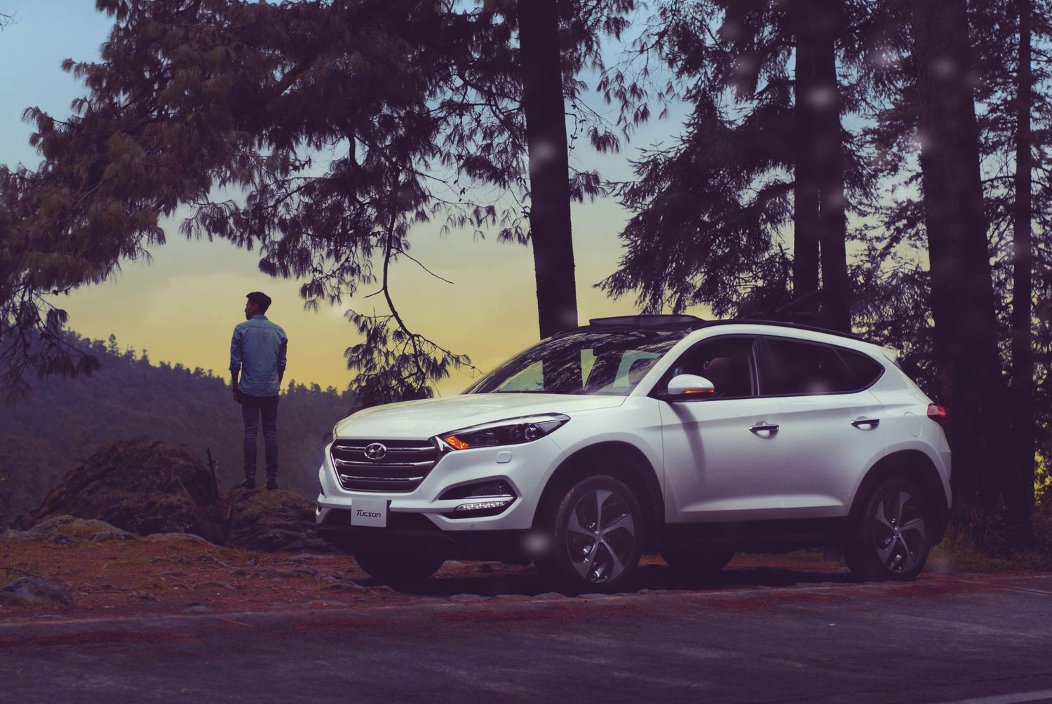 The Hyundai Tucson appears in multiple shots driving along scenic mountain roads against a dusky sky at sunset.