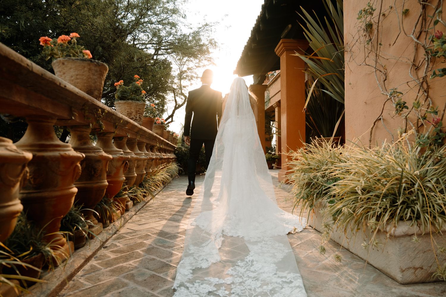 Sunset wedding photo showing long veil trailing down terra cotta steps with decorative railings.