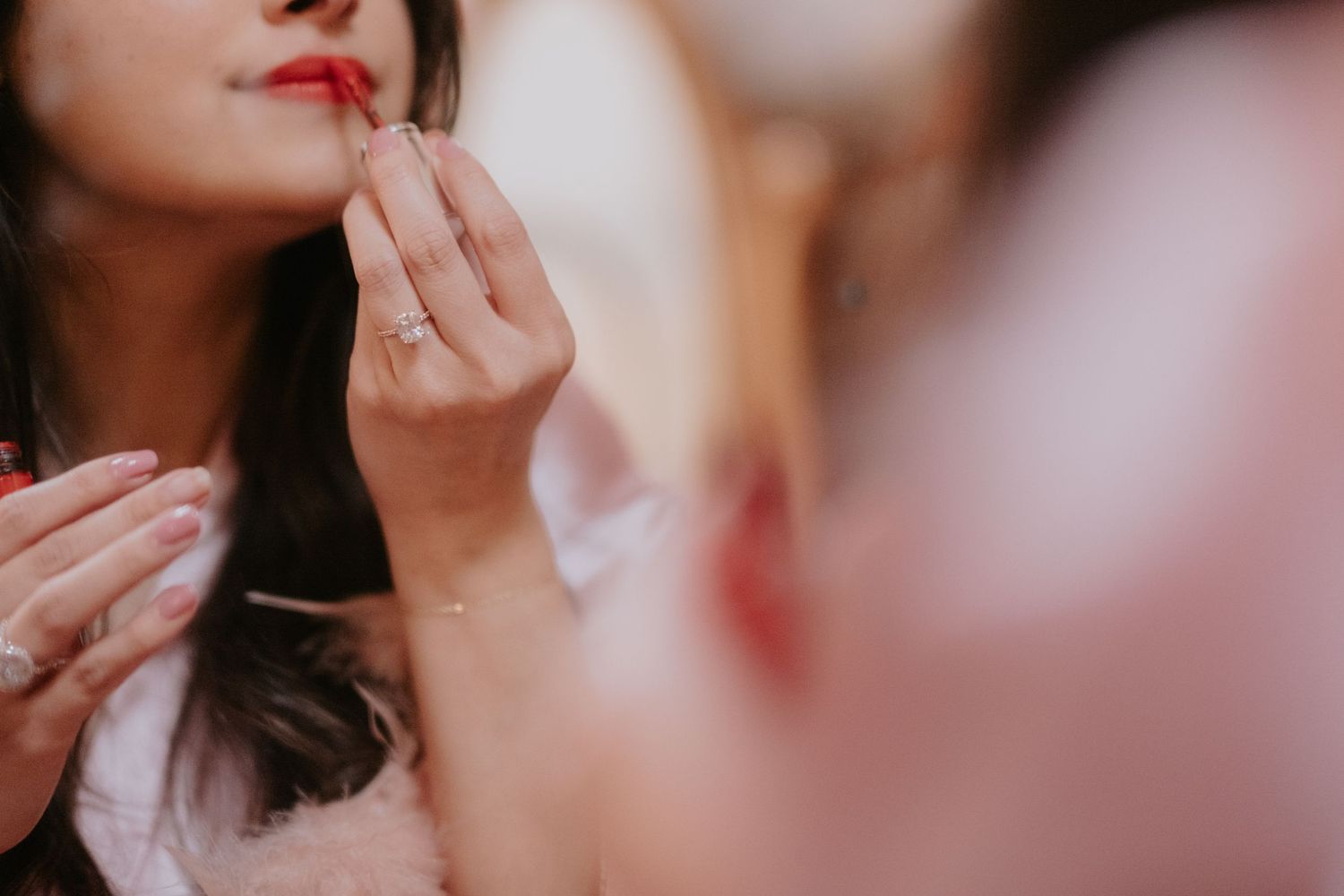 Close-up shot of someone applying red lipstick in soft focus.