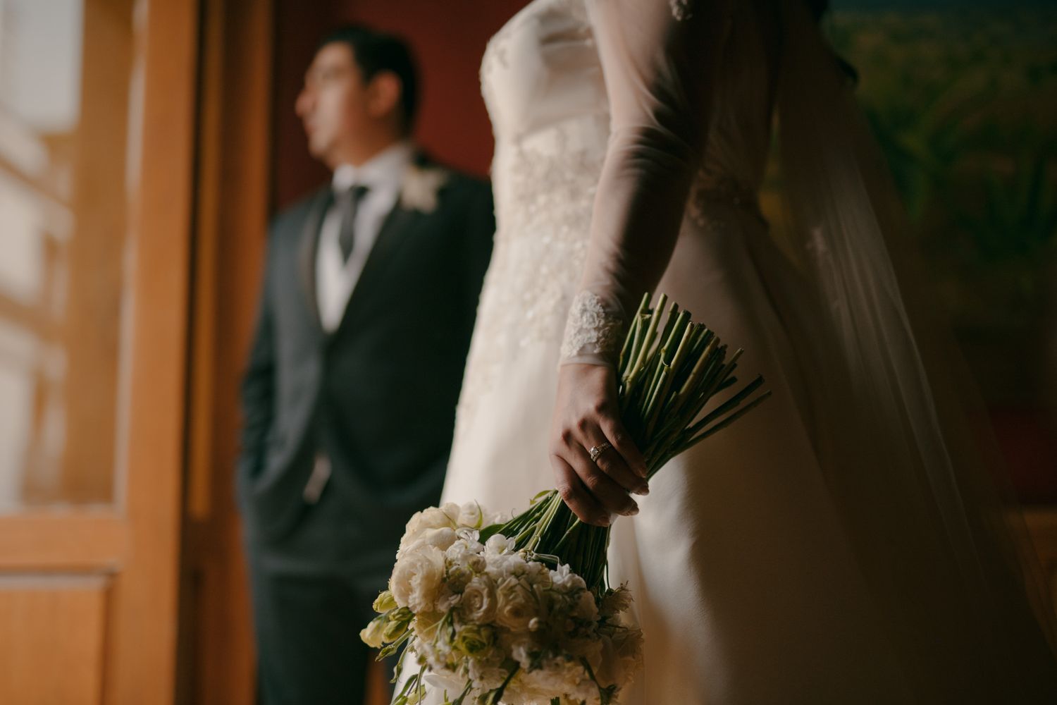 Intimate wedding moment with bouquet of white flowers and formal attire.