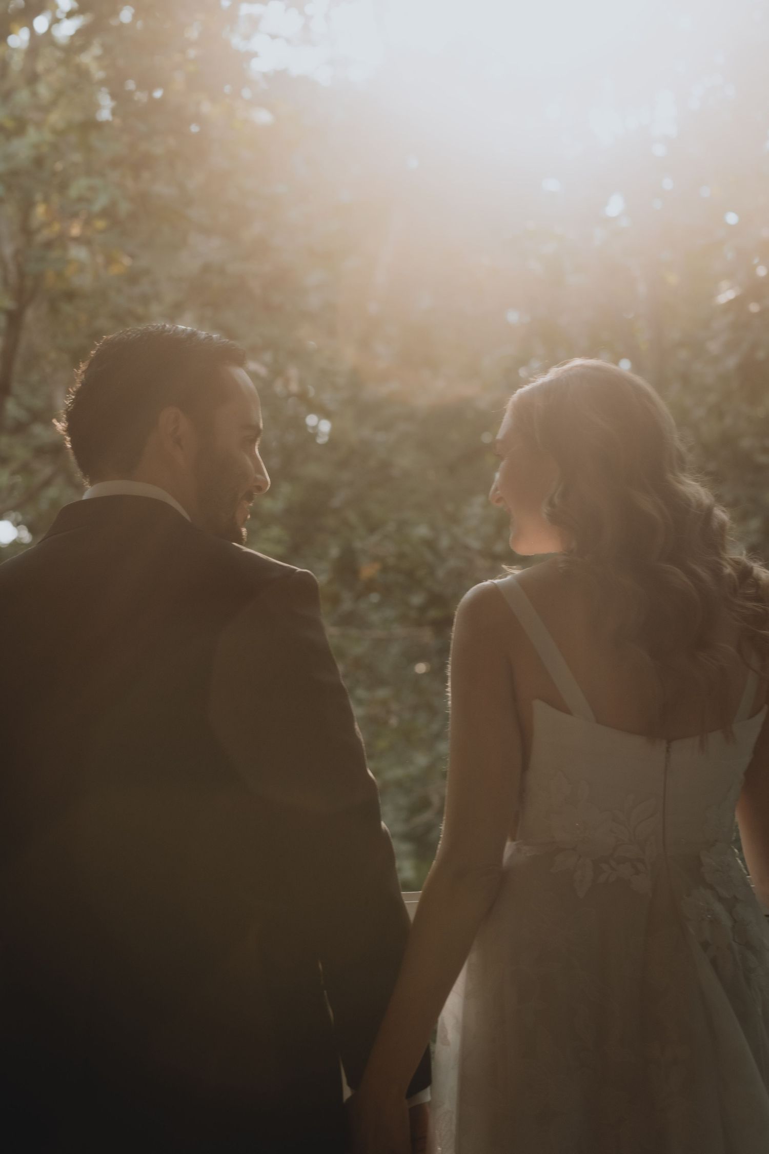 Romantic sunset portrait of wedding couple walking together in garden setting.
