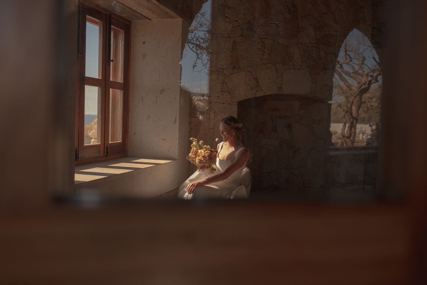 A person sits by a sunny window in an old stone building, creating a peaceful, contemplative atmosphere.
