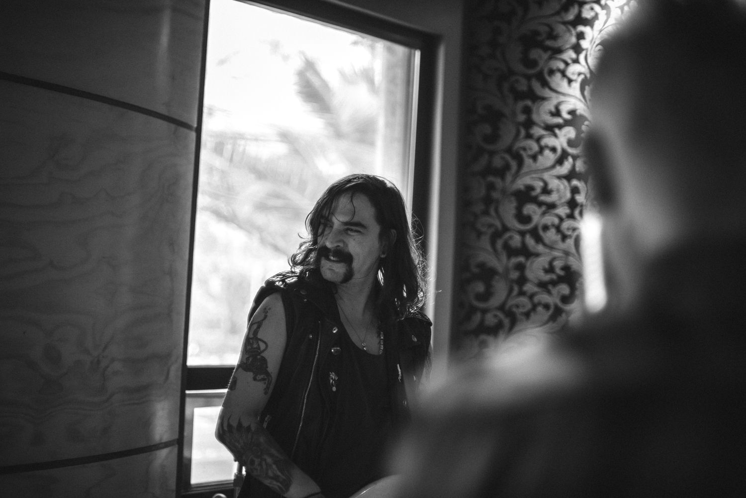 Black and white photo of vocalist performing with window light in recording studio setting.