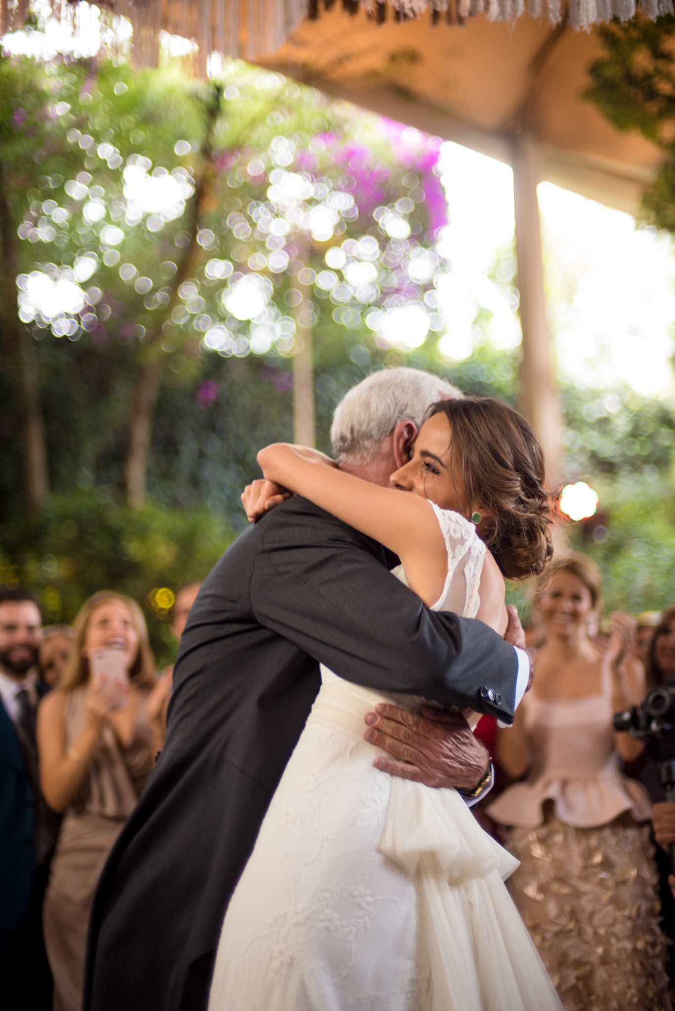 An emotional embrace during a father-daughter dance at an outdoor wedding reception.