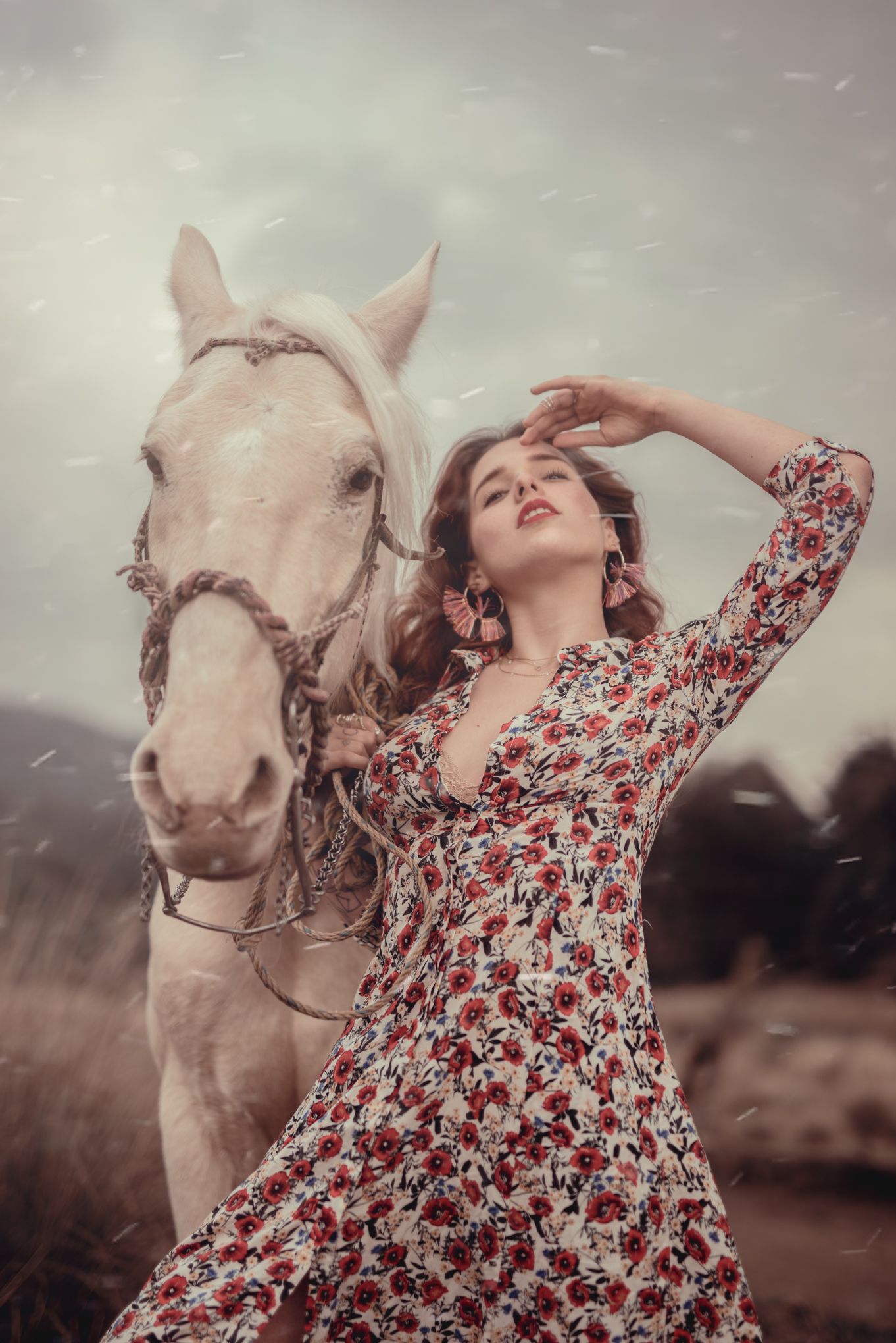 Dreamy portrait with white horse and floral dress in misty natural setting.