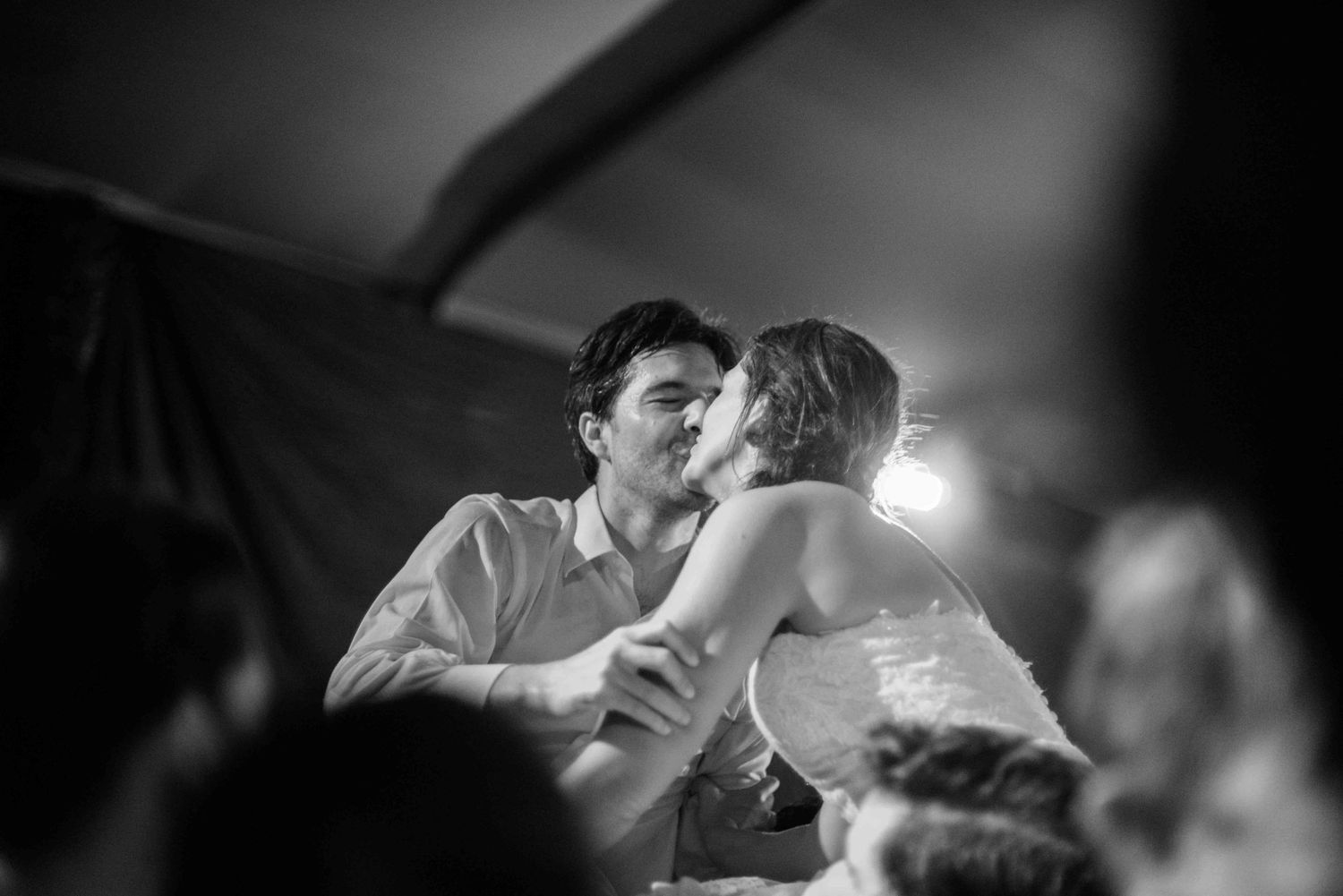 A romantic black and white photo of a couple sharing a tender moment while dancing at an intimate gathering.