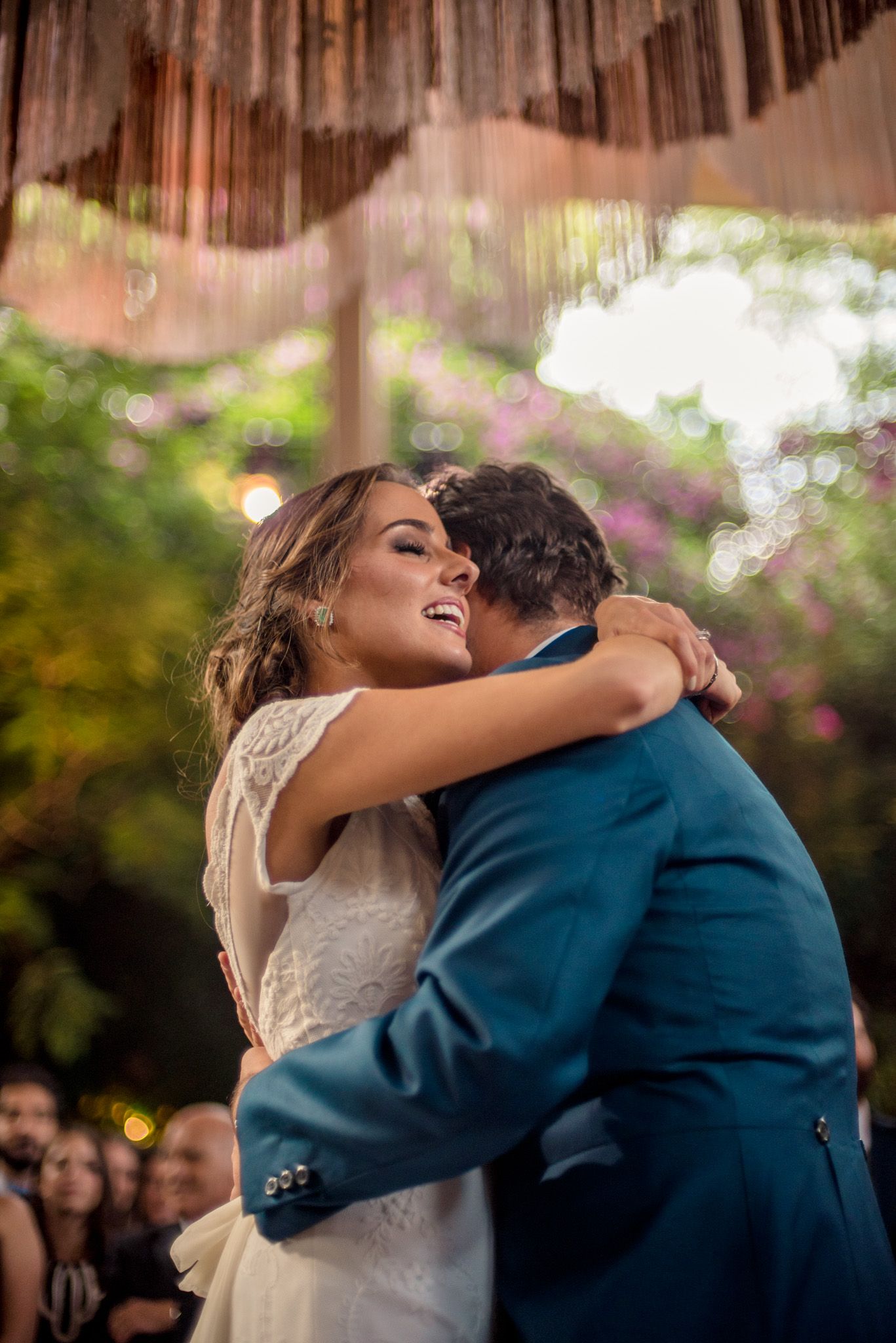 A joyful wedding dance moment captured outdoors under string lights and natural garden surroundings.