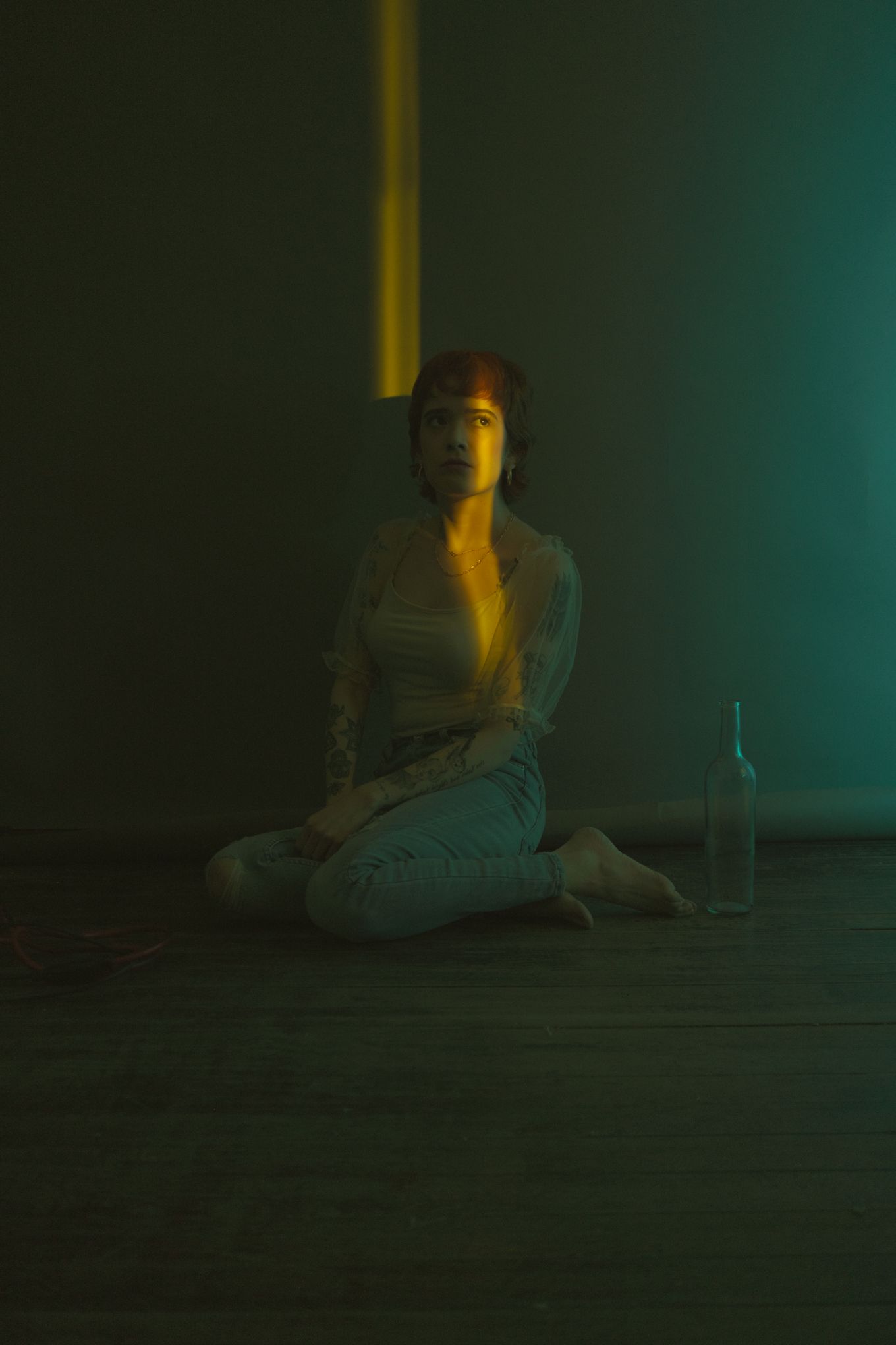 Low-key portrait in dark room with green and amber lighting effects.