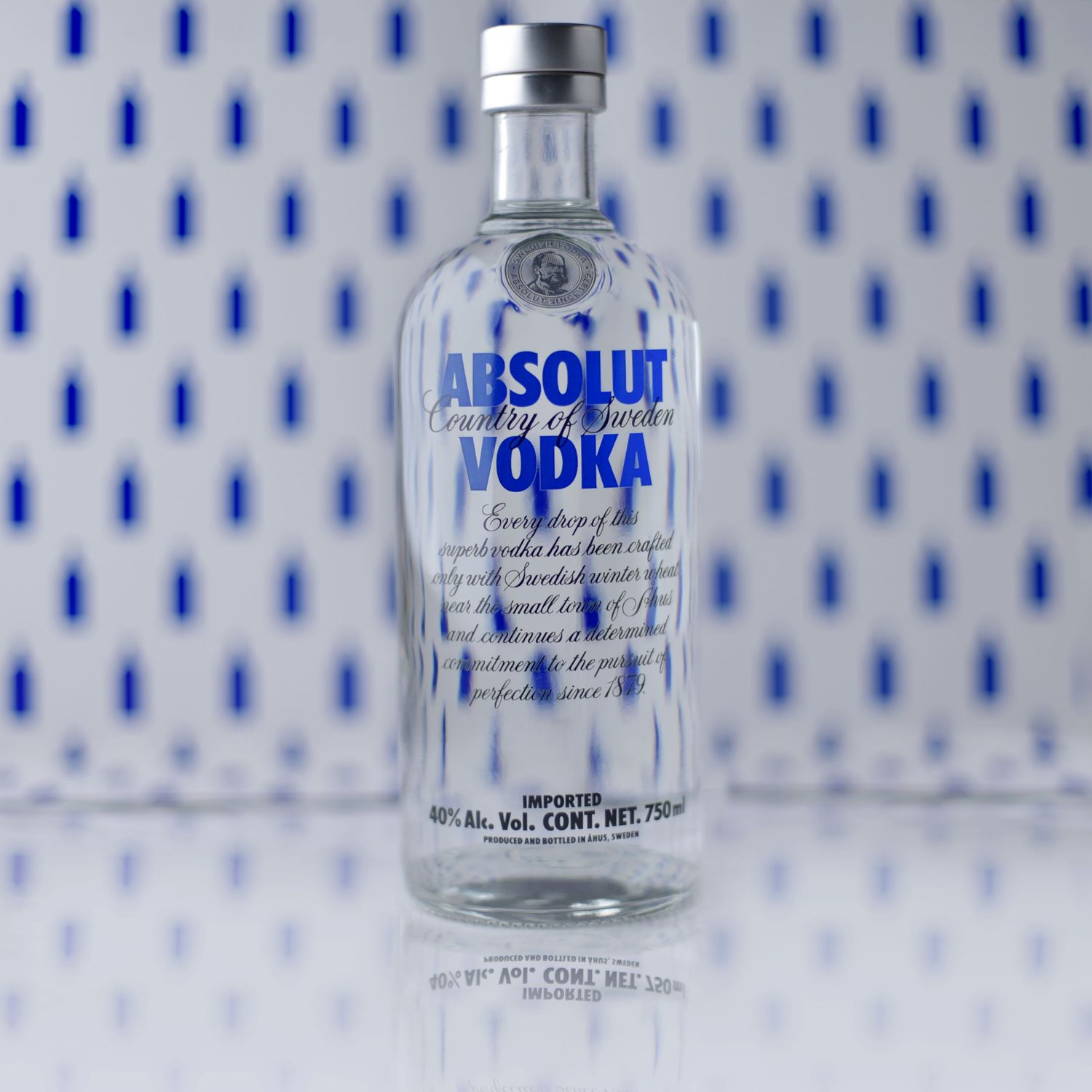 Absolut vodka bottle displayed against blue and white patterned background.