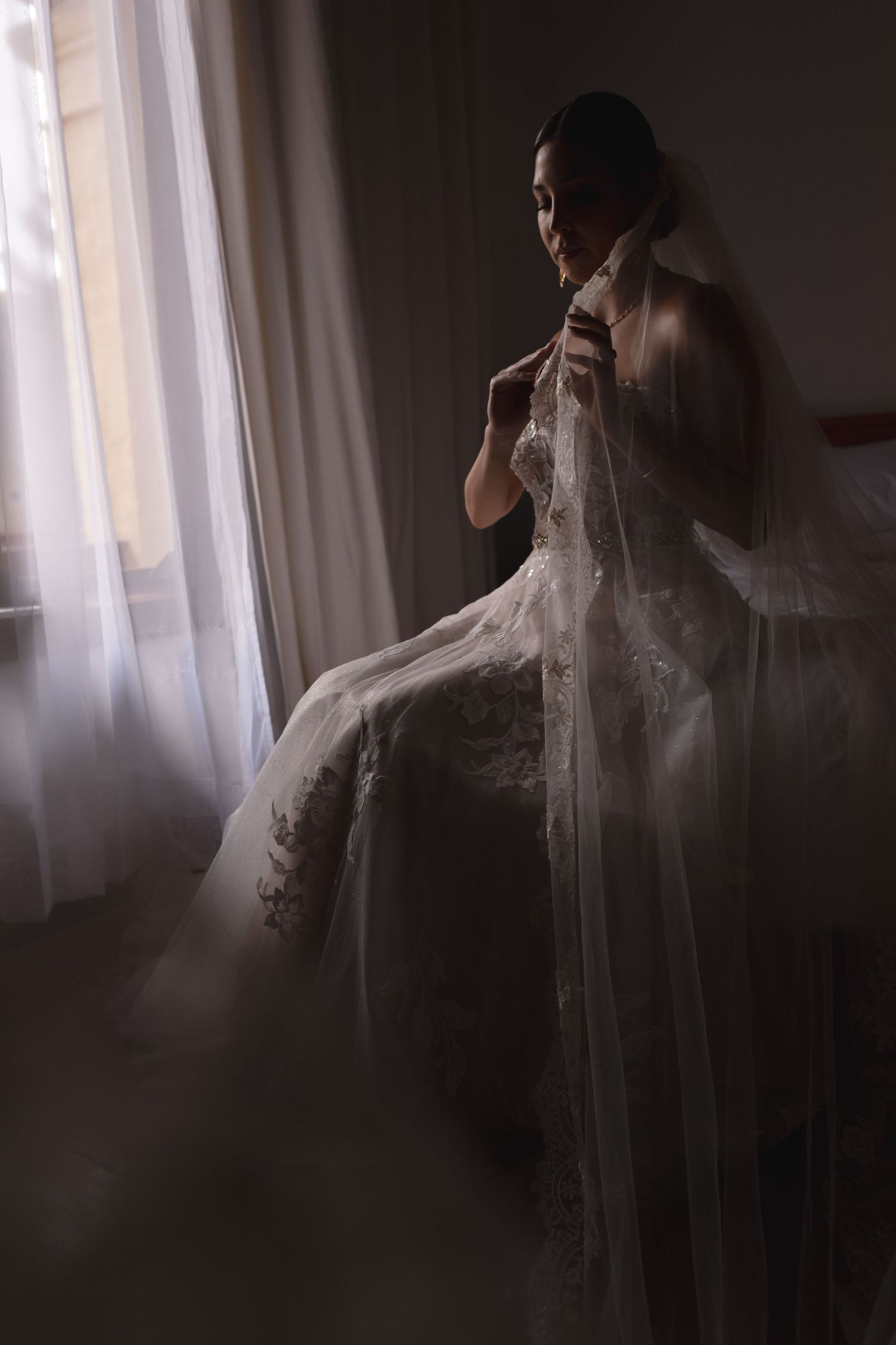 Moody boudoir-style portrait of a bride in delicate lace and tulle.