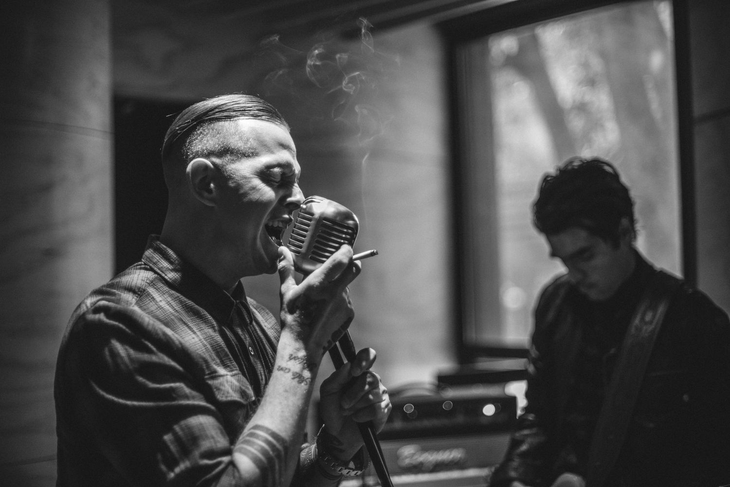 Dramatic black and white image of a vocalist singing into a vintage microphone.