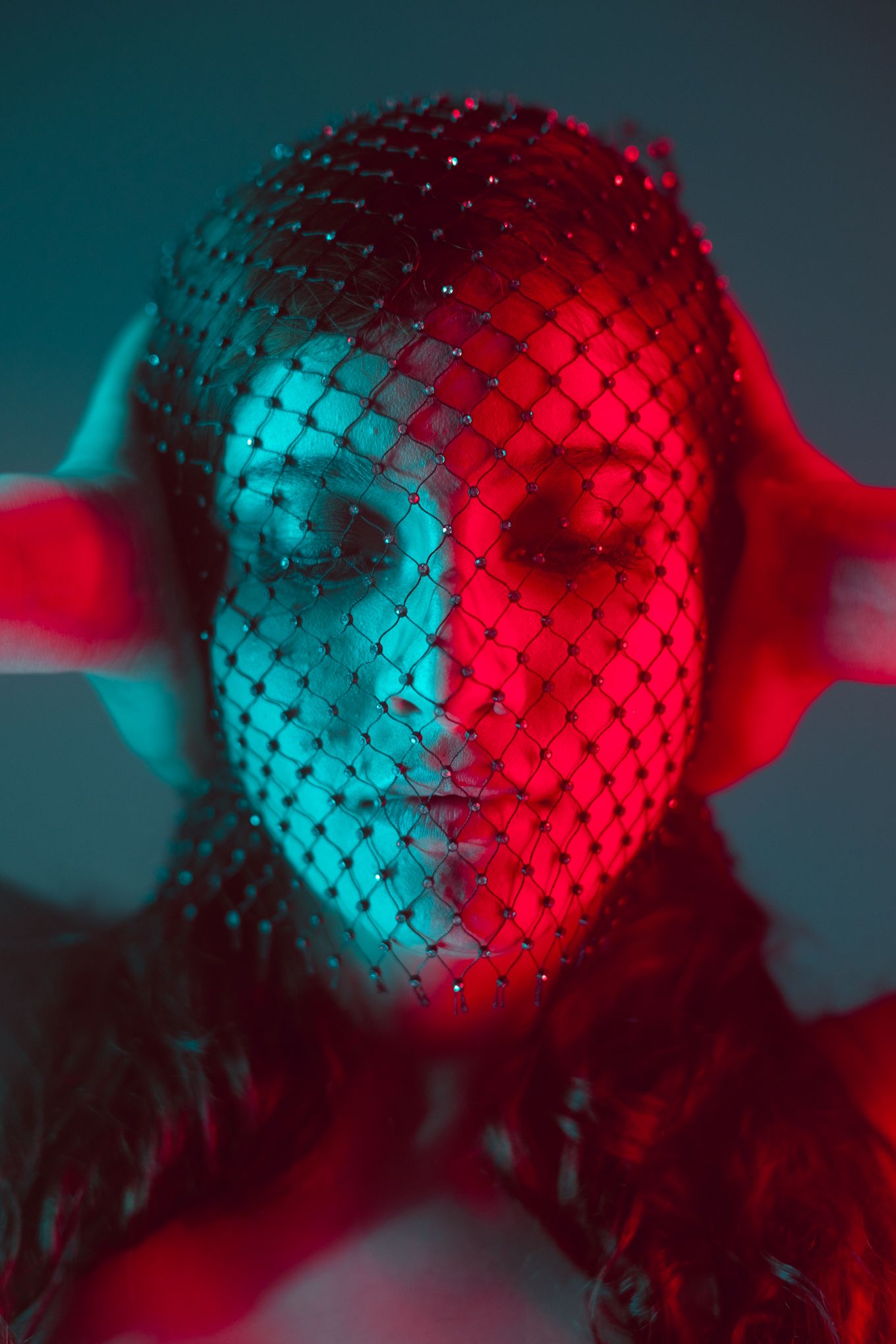 Dramatic portrait with mesh mask effect illuminated by contrasting red and blue lighting.