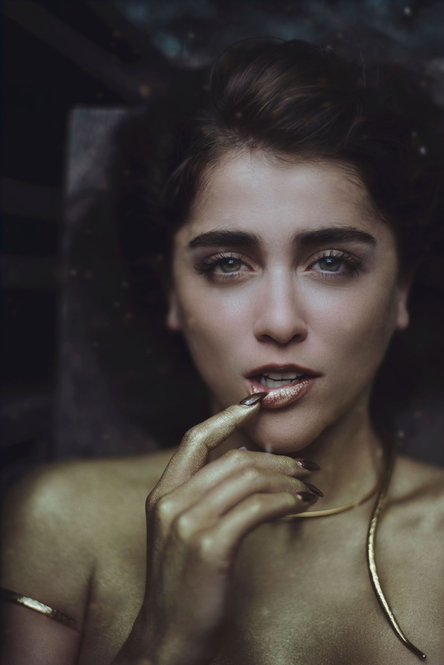Dramatic close-up portrait with gold tones and moody lighting.