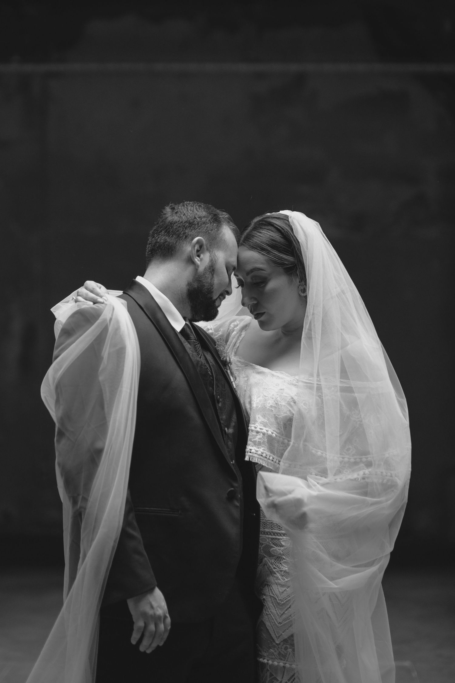 Intimate black and white moment between newlyweds with bride wearing flowing veil.