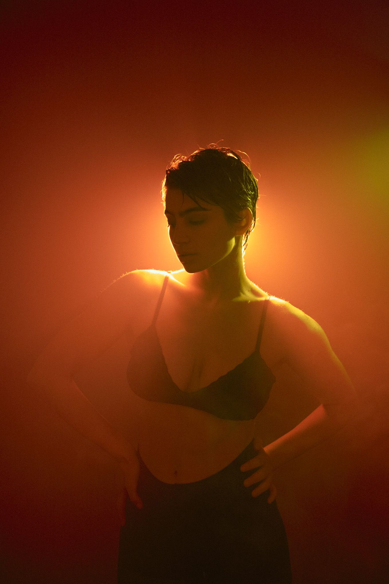 Silhouette portrait bathed in warm orange backlighting creating ethereal atmosphere.