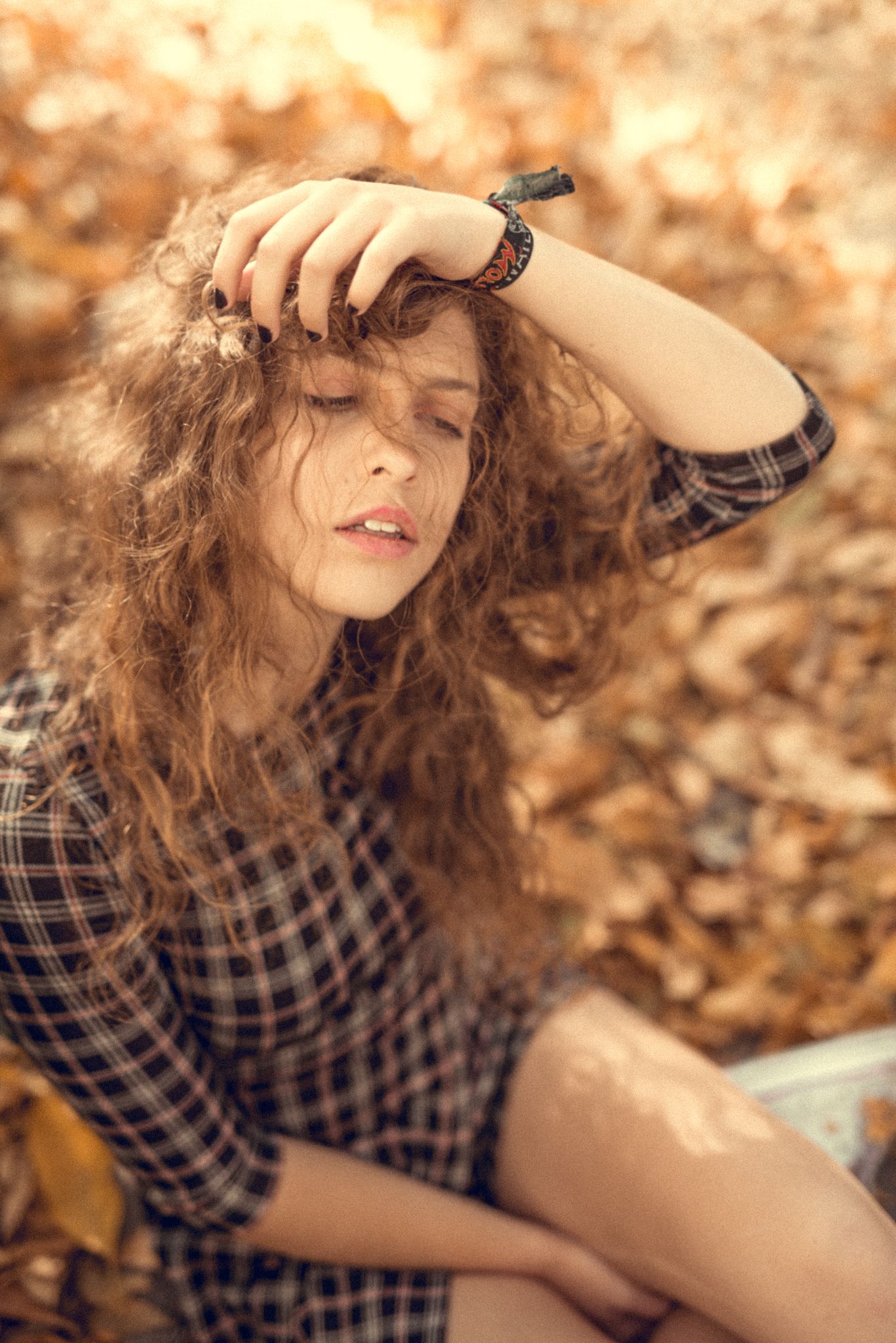 Dreamy autumn portrait with curly hair in dappled sunlight.