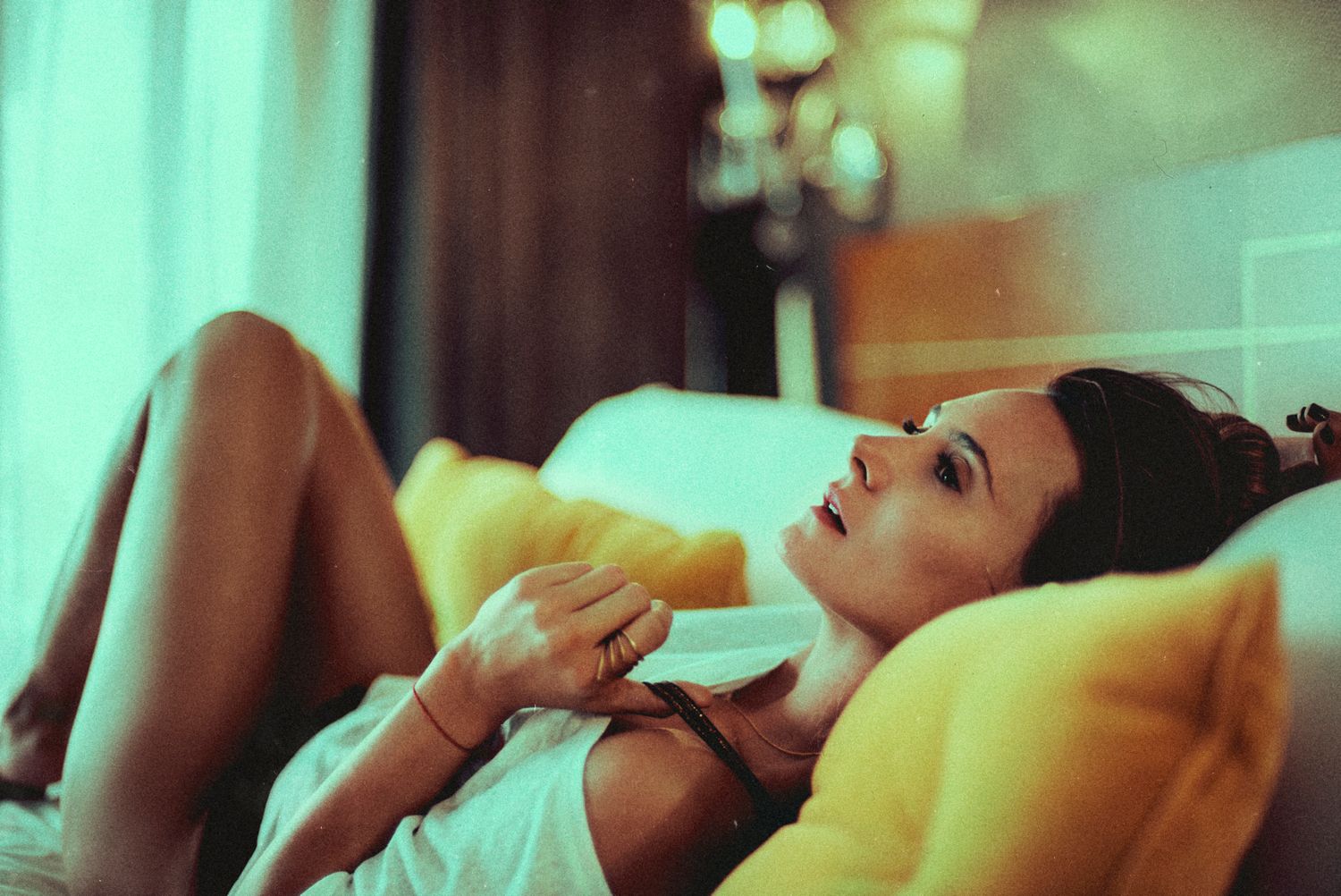 Dreamy boudoir photo with soft lighting and relaxed pose on yellow-tinted couch.